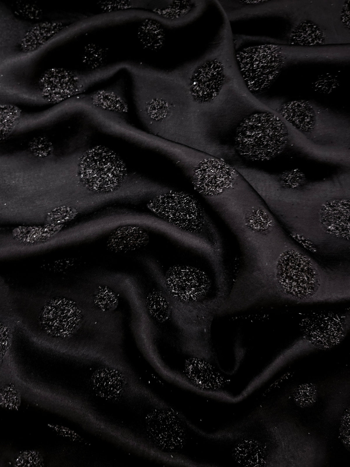 Black viscose metallic jacquard close-up showing metallic confetti motifs woven into the surface.