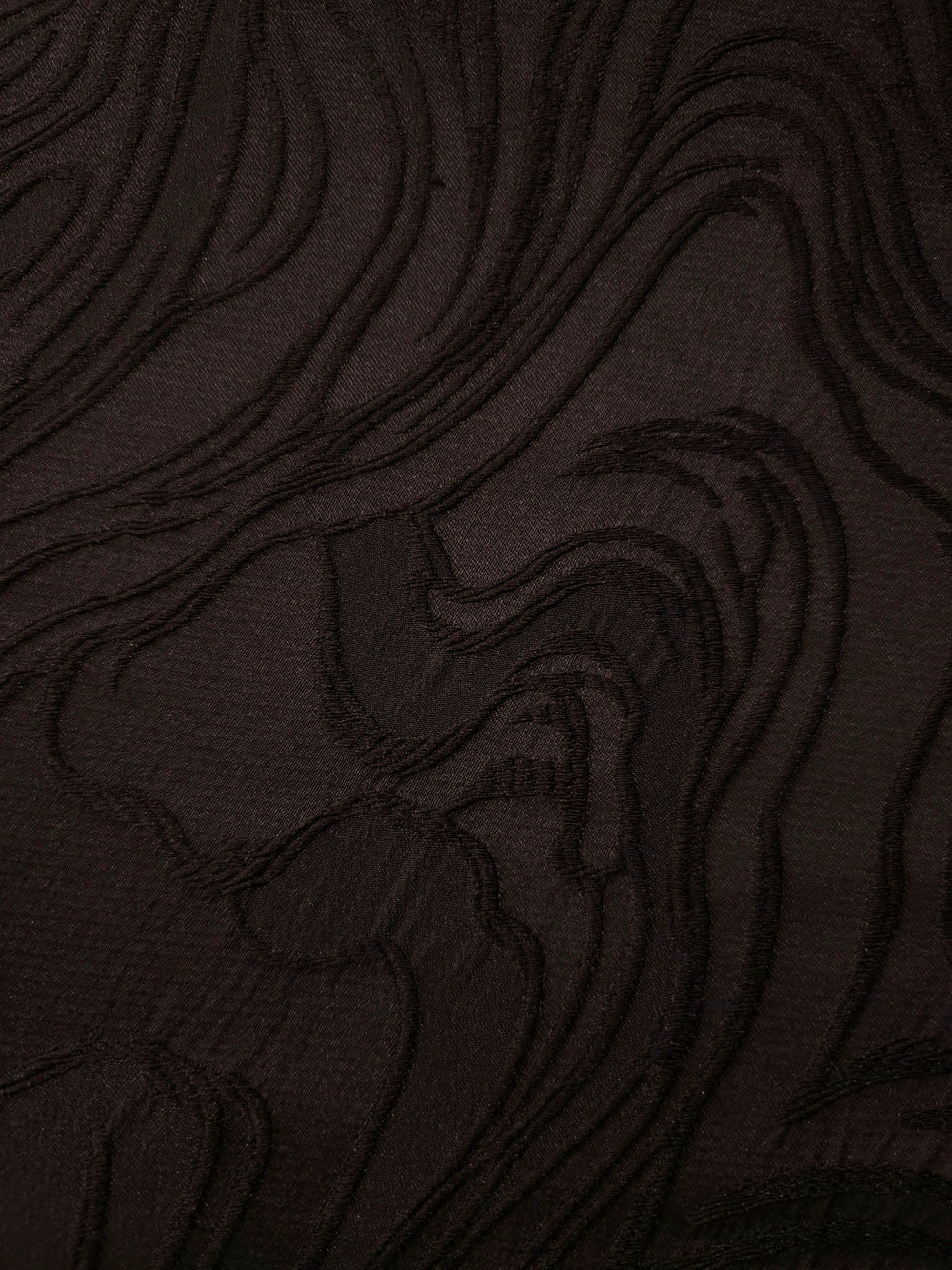 Drape view of brown branch polyester crepe jacquard fabric showing its textured woven surface.