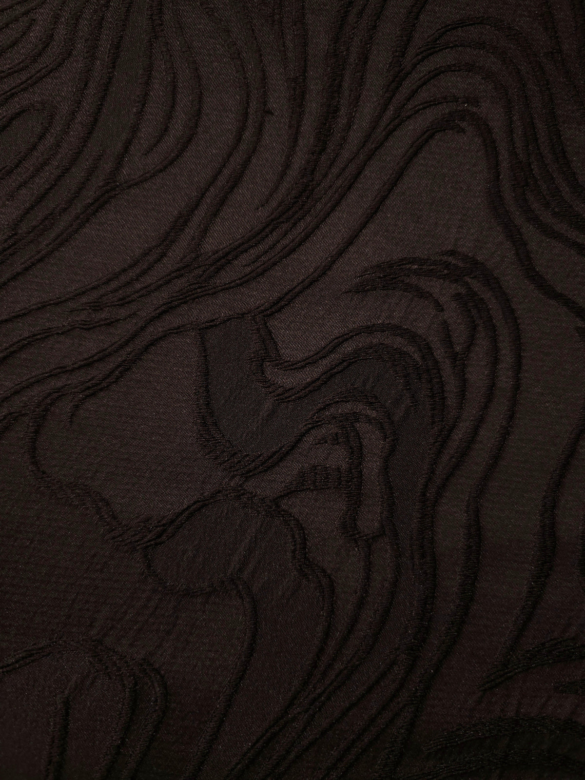 Drape view of brown branch polyester crepe jacquard fabric showing its textured woven surface.