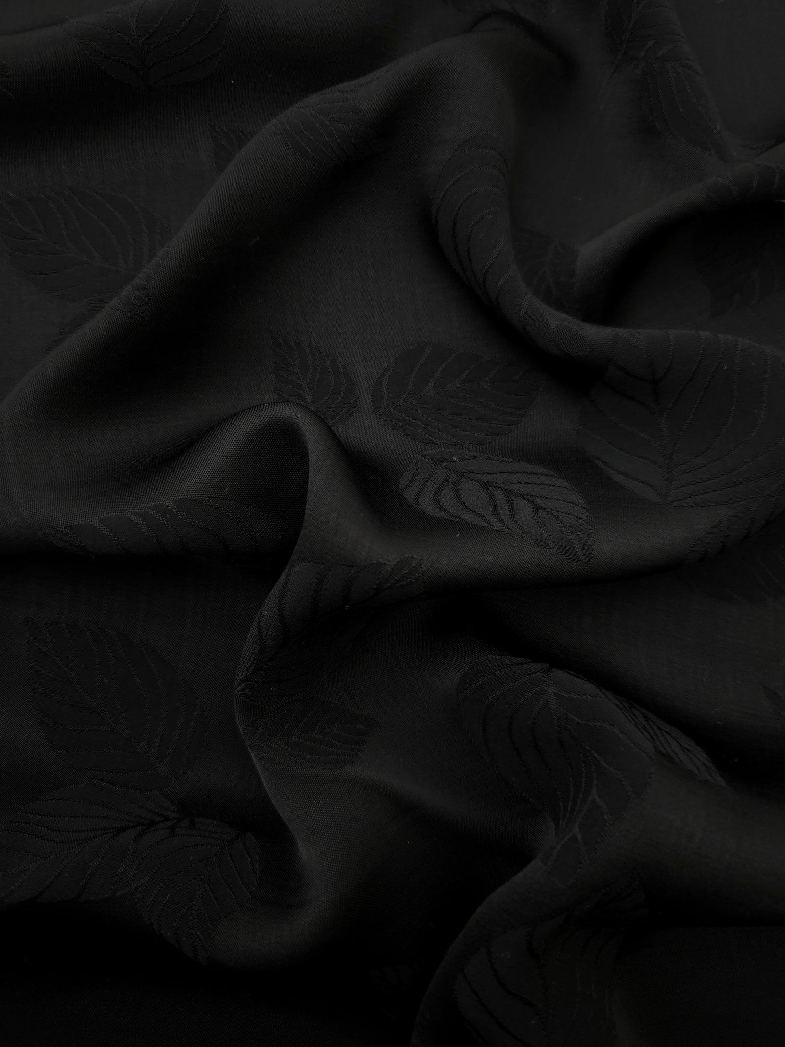 Black botanical leaf print viscose fabric with fluid garment drape