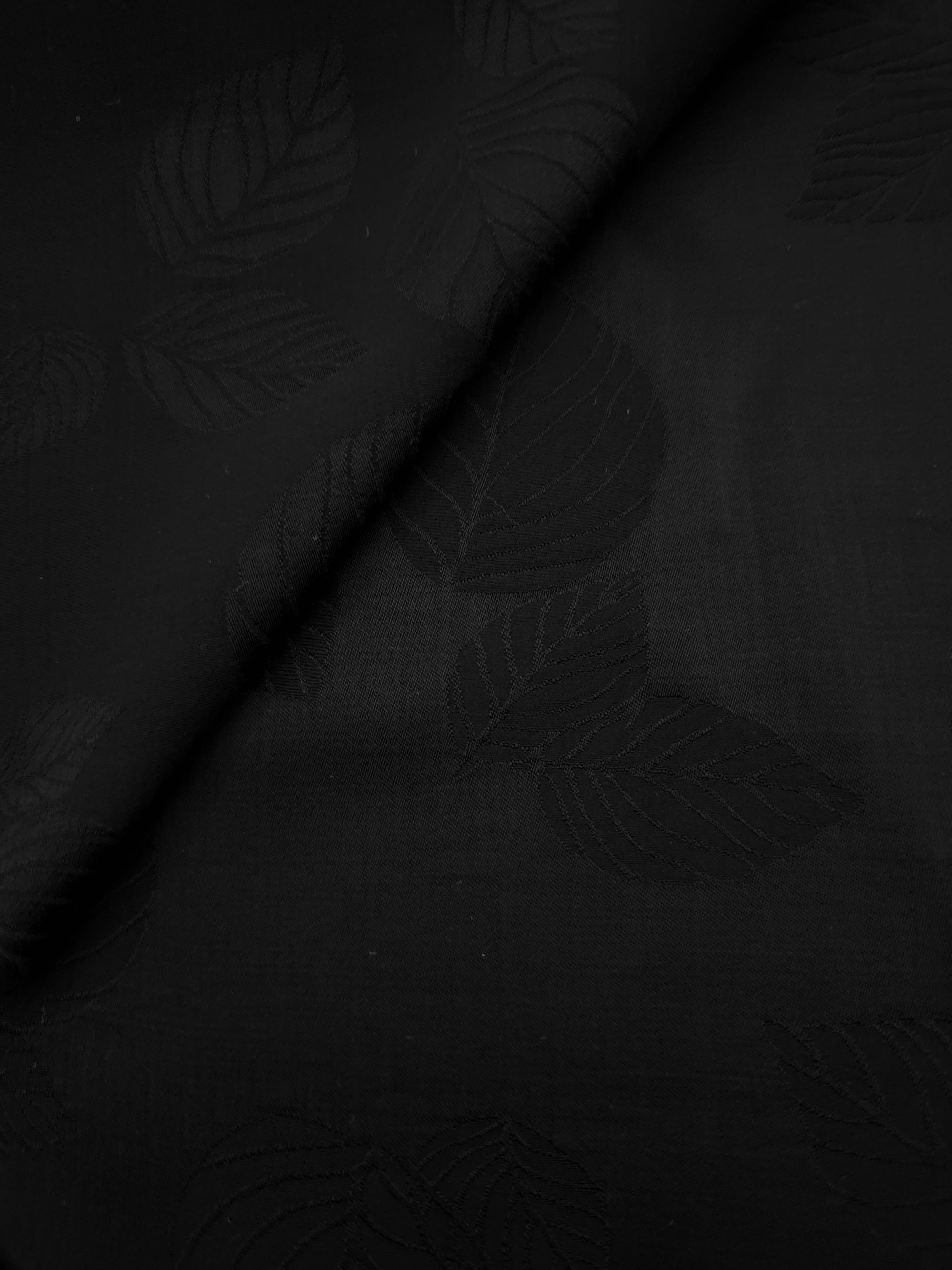 Close-up of black botanical leaf print on soft 100% viscose fabric