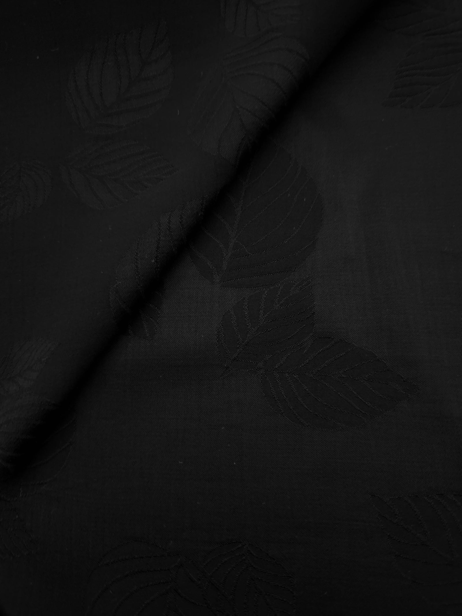 Close-up of black botanical leaf print on soft 100% viscose fabric