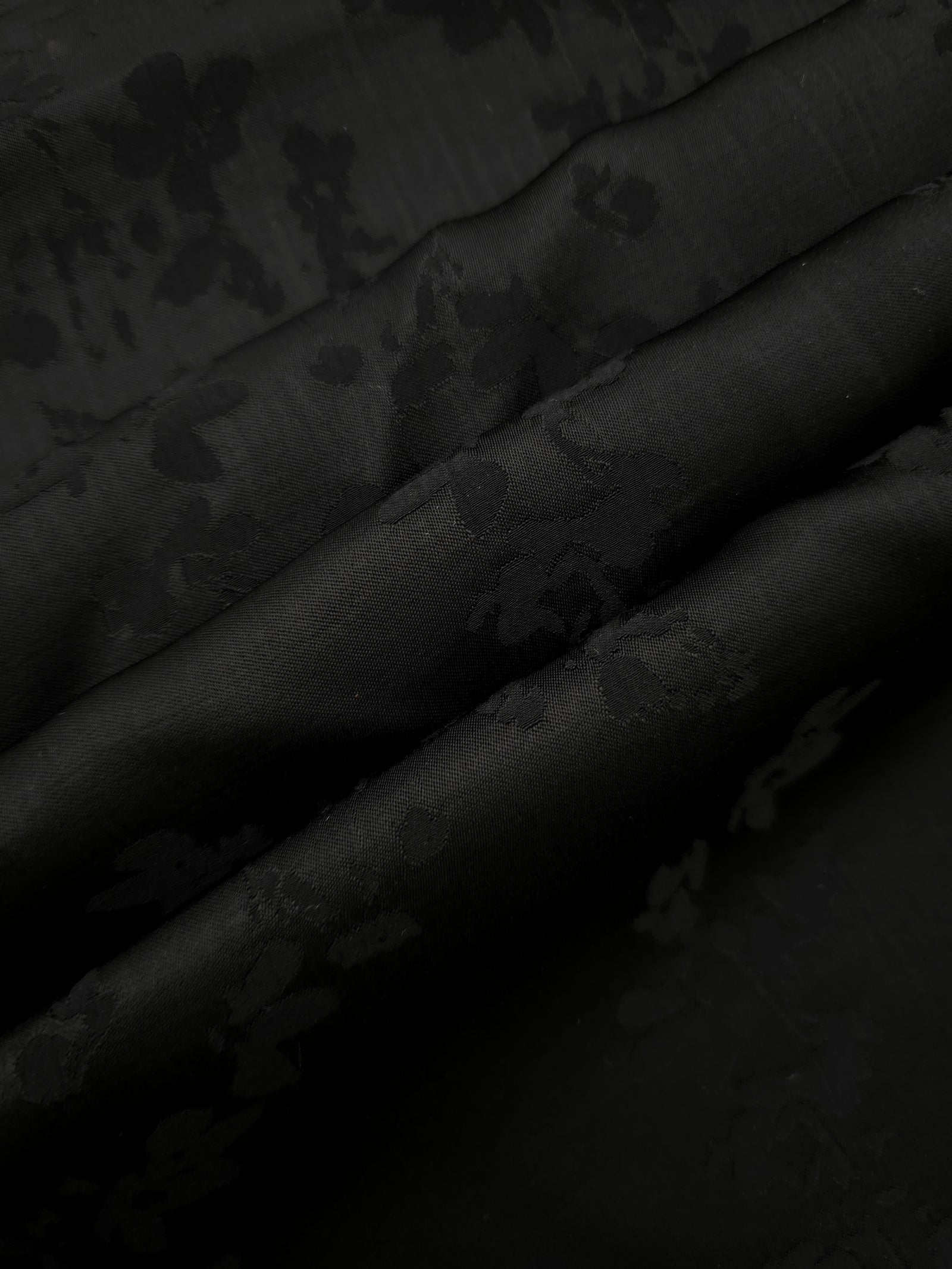 Detailed black petal flower print viscose fabric showing floral motif