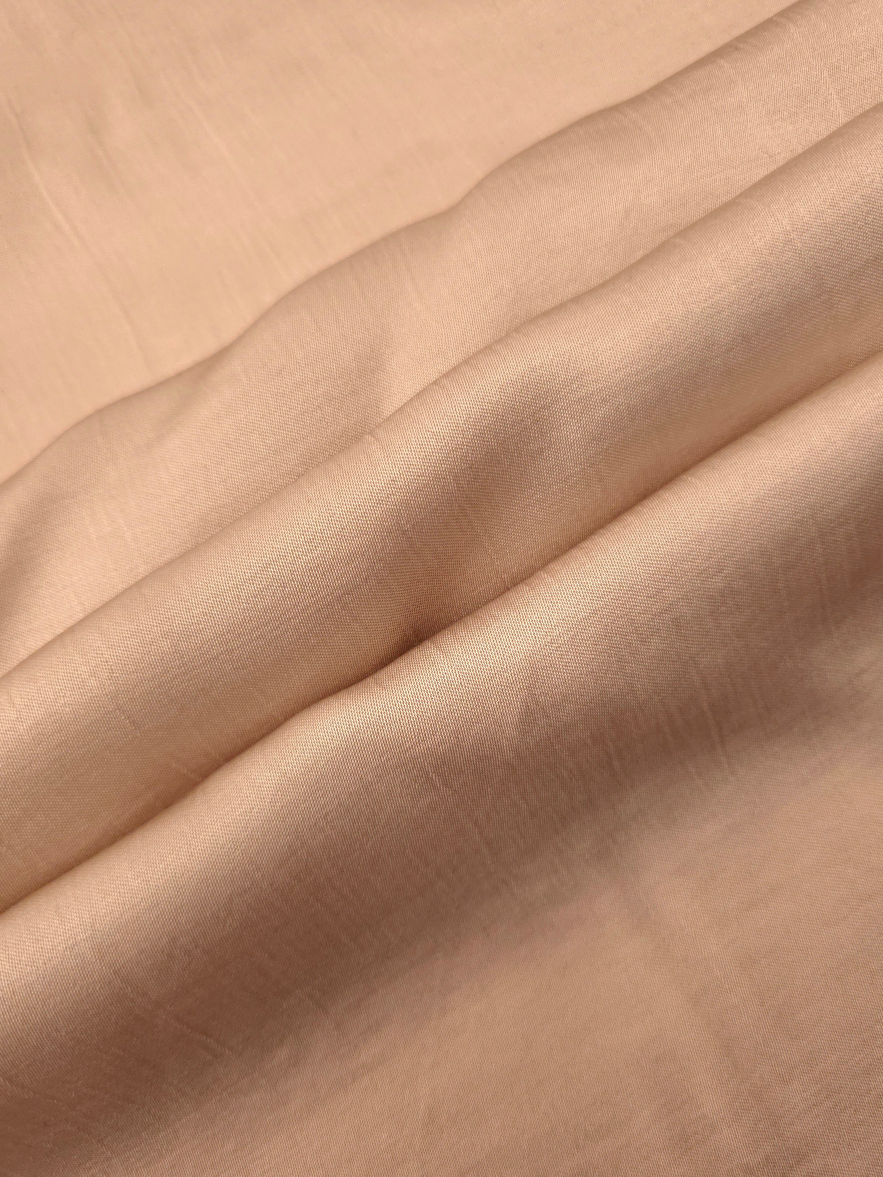 Flowy warm beige plain viscose fabric showing soft fluid texture