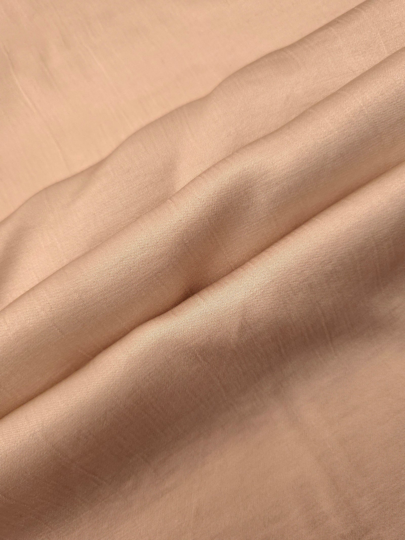 Flowy warm beige plain viscose fabric showing soft fluid texture