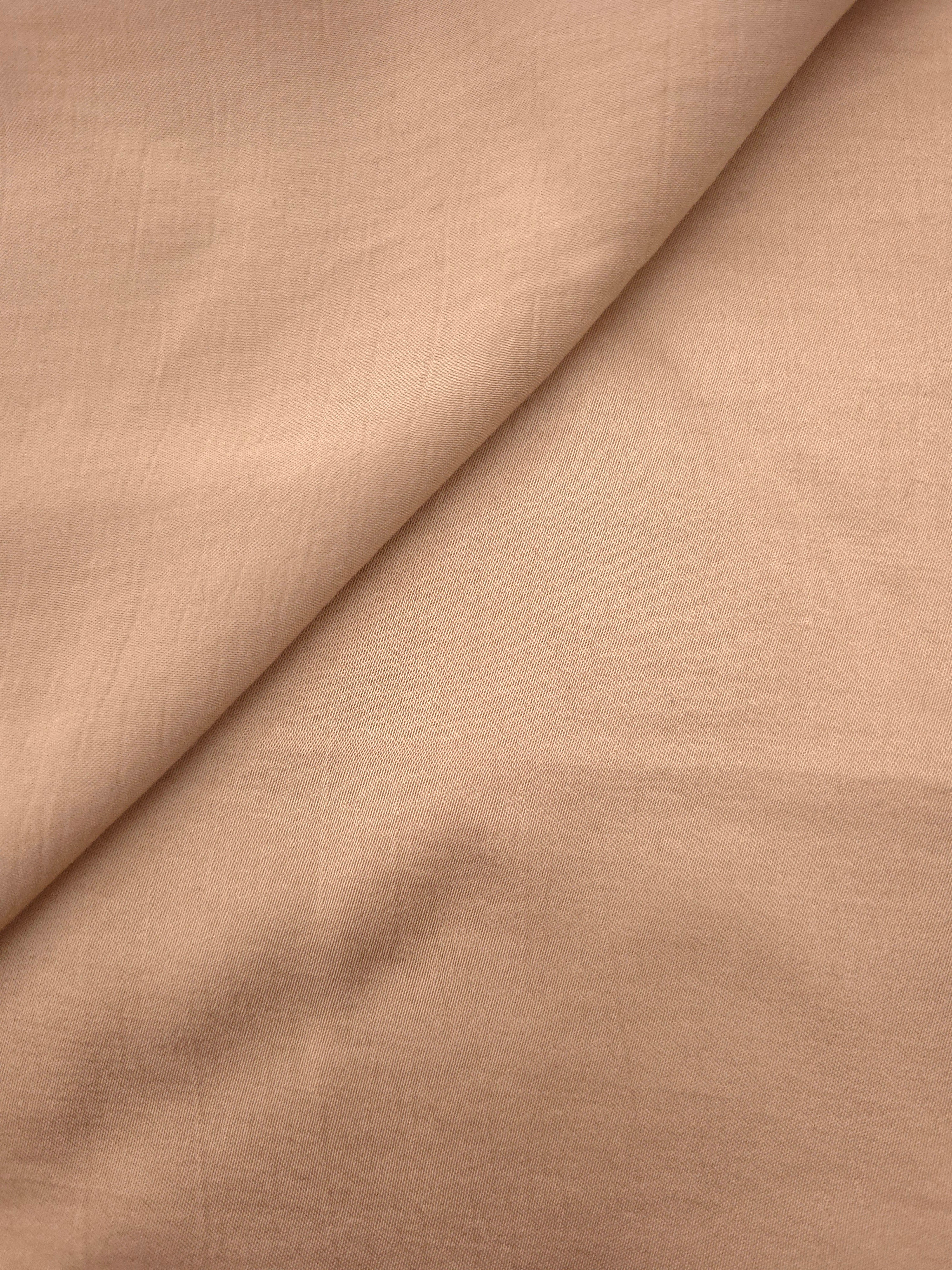 Close-up of warm beige plain viscose fabric showing natural woven texture