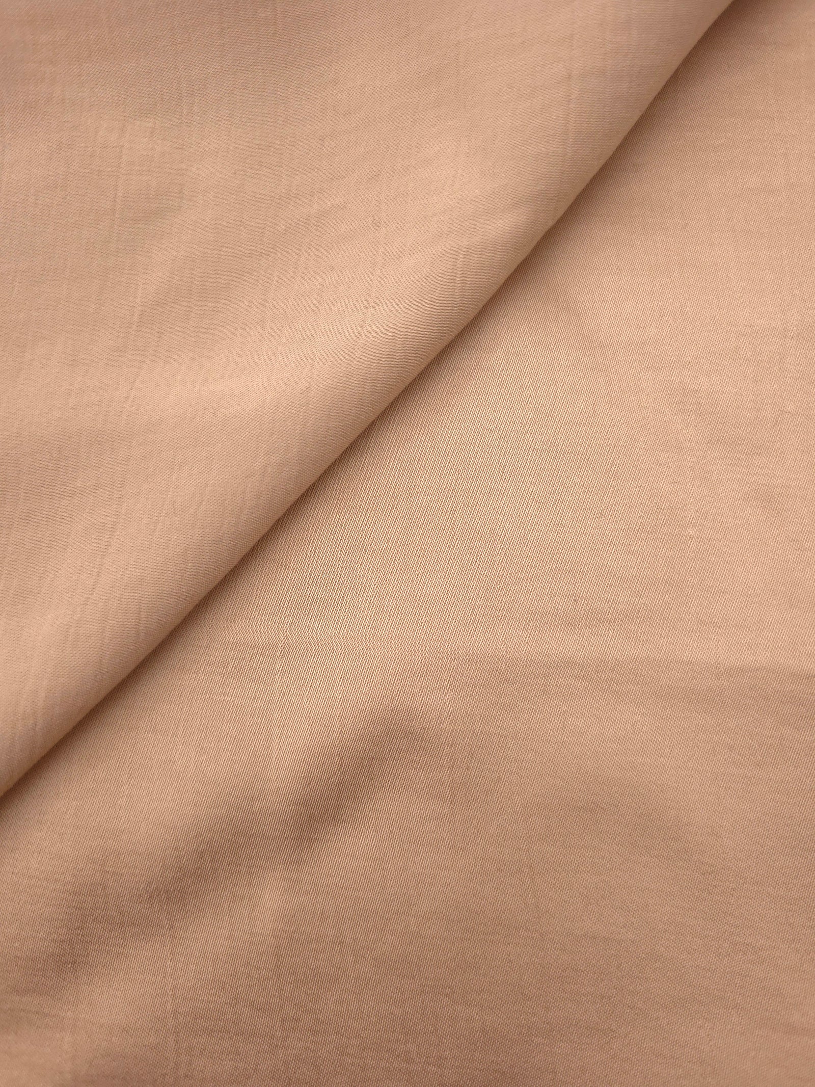 Close-up of warm beige plain viscose fabric showing natural woven texture