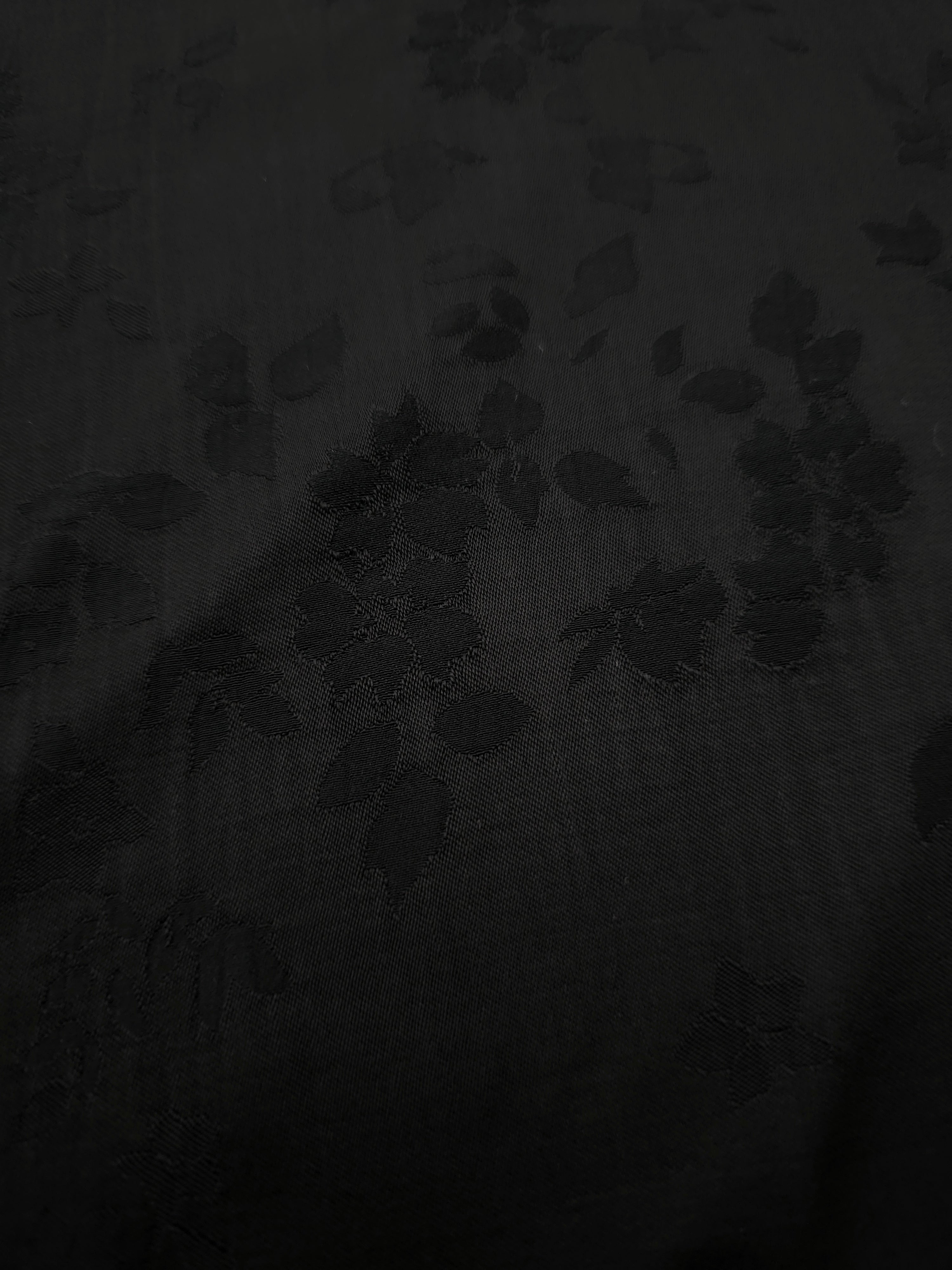 Close-up of black stylized leaf print on soft 100% viscose fabric