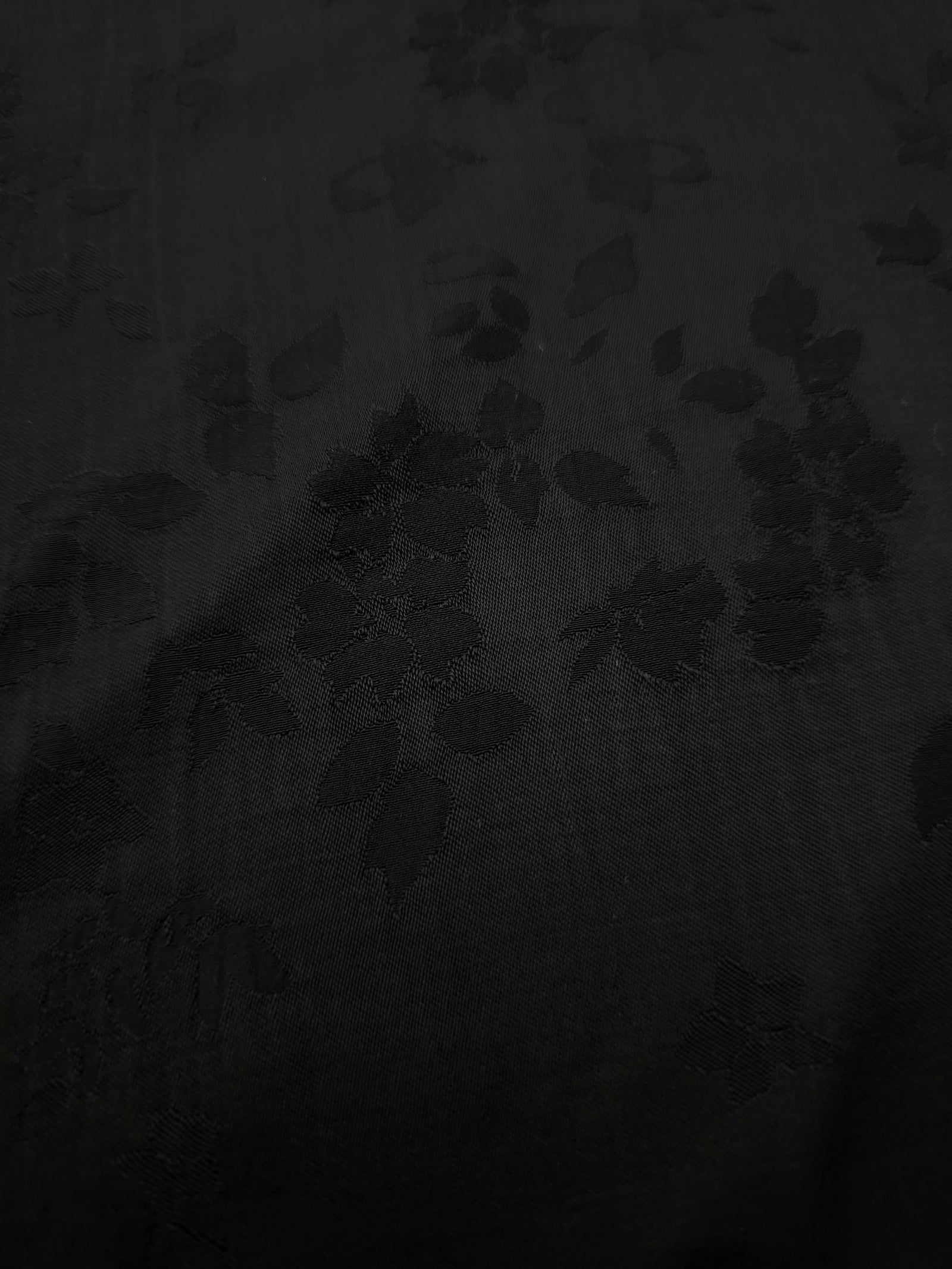 Close-up of black stylized leaf print on soft 100% viscose fabric