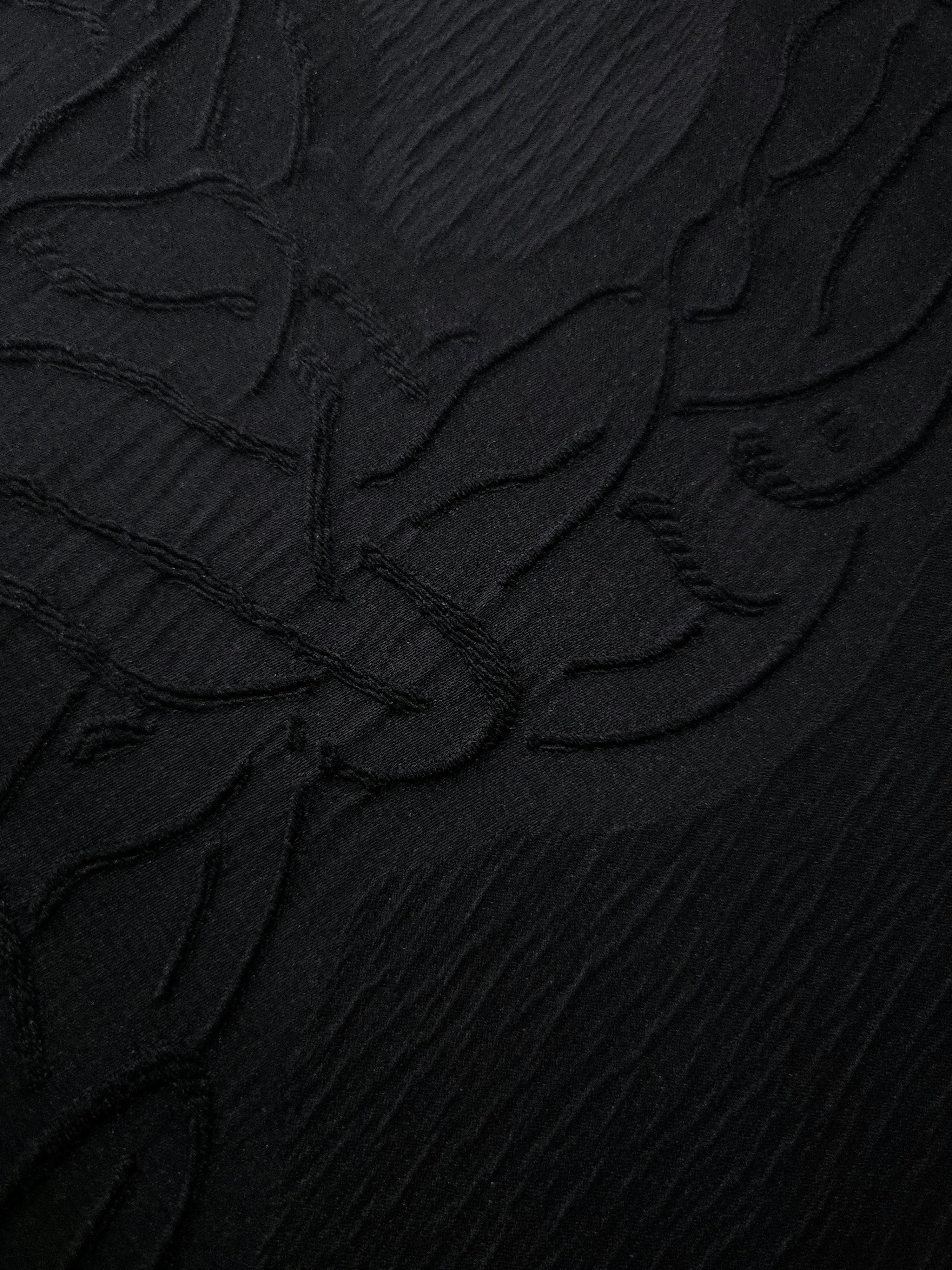 Pattern detail of black laurel polyester crepe jacquard fabric with raised woven texture.