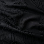 Wide view of black laurel polyester crepe jacquard fabric for tailored modestwear layers.