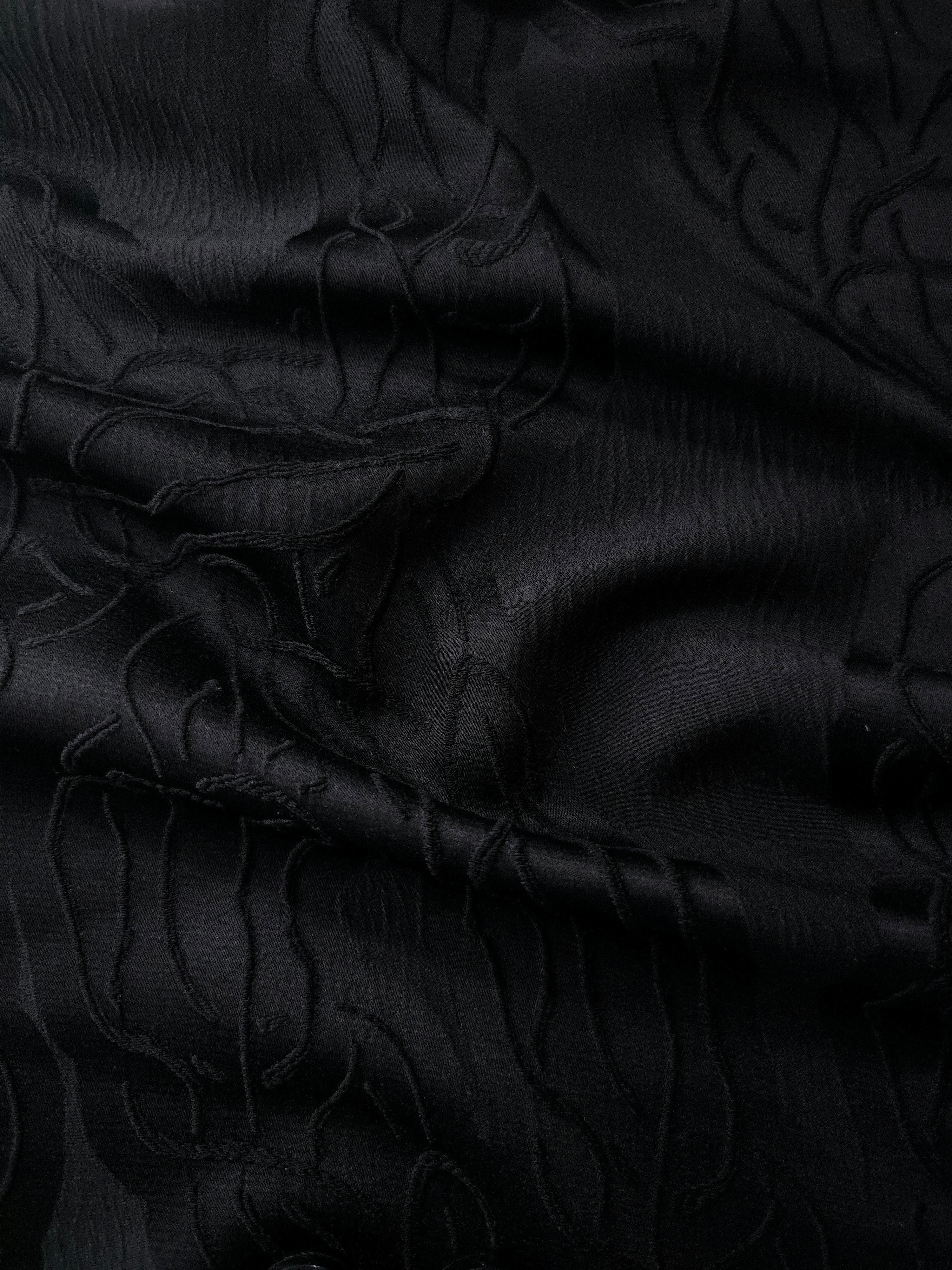Wide view of black laurel polyester crepe jacquard fabric for tailored modestwear layers.