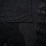 Closeup texture of black laurel polyester crepe jacquard fabric for structured dress layers.