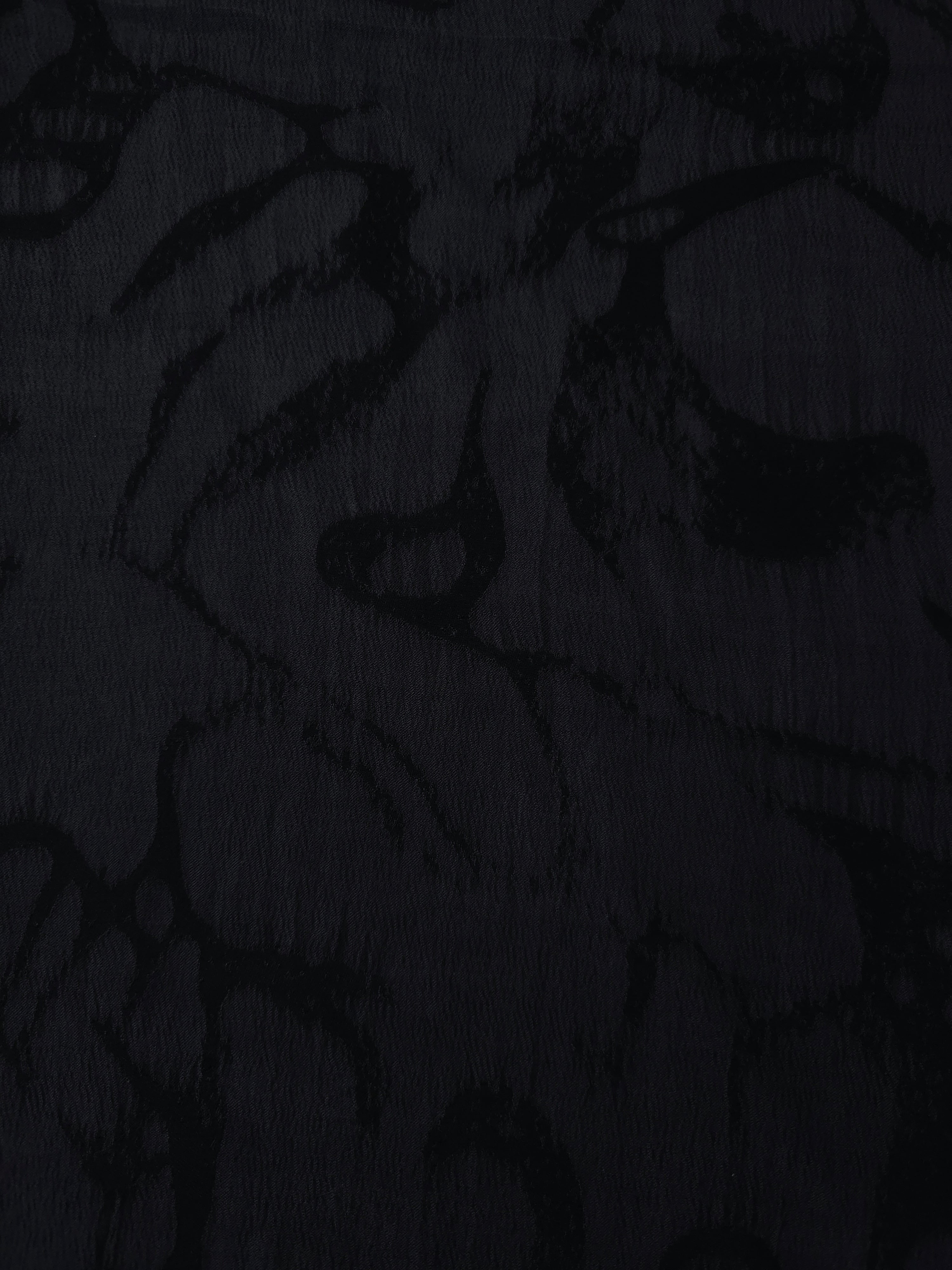 Black abstract scroll lyocell viscose jacquard showing tonal woven pattern for dress fabric.