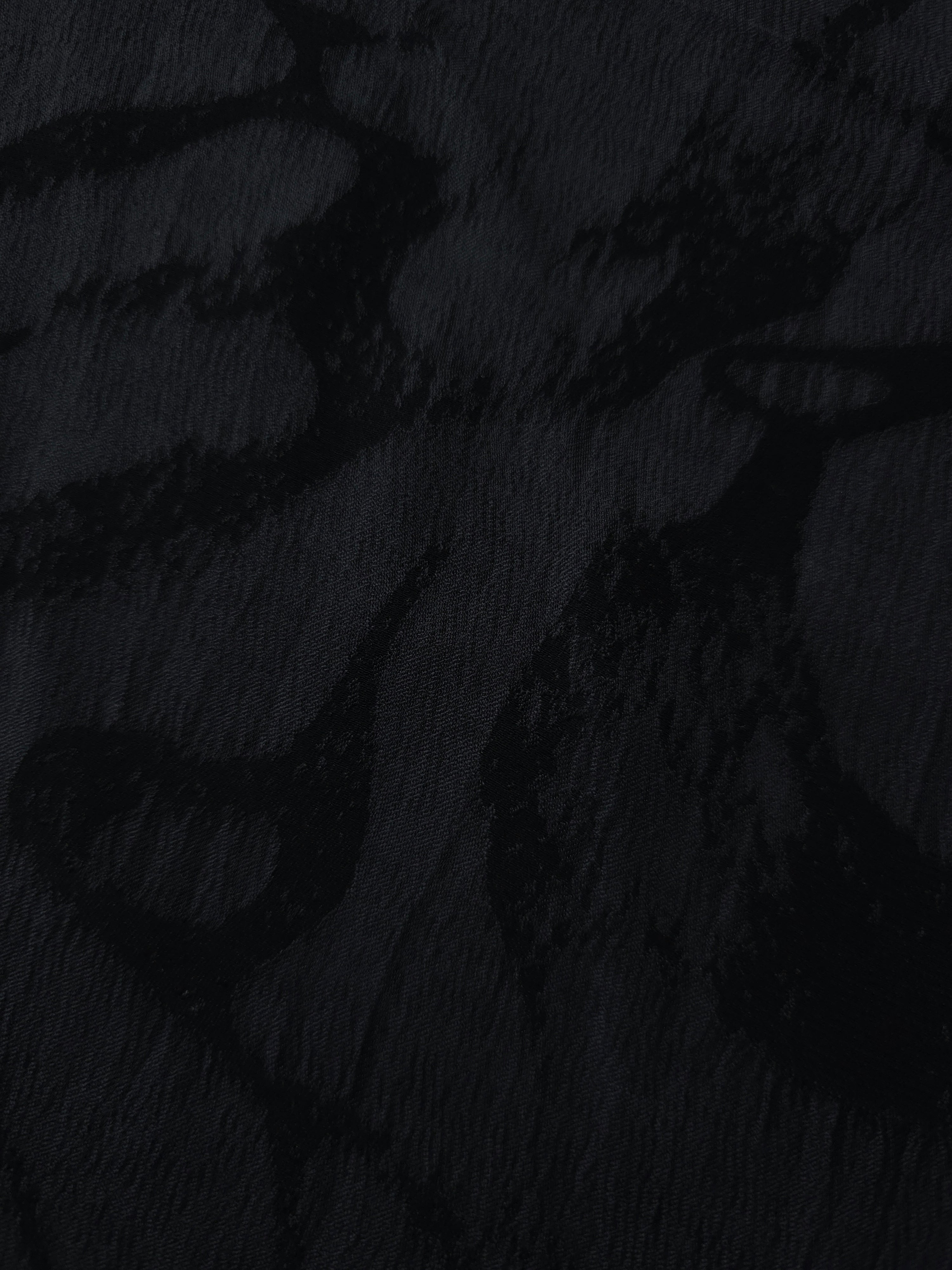 Close texture of black abstract scroll jacquard with darker pattern on lyocell viscose base.