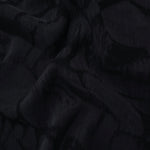 Draped black abstract scroll jacquard showing fluid texture for dresses and blouses.