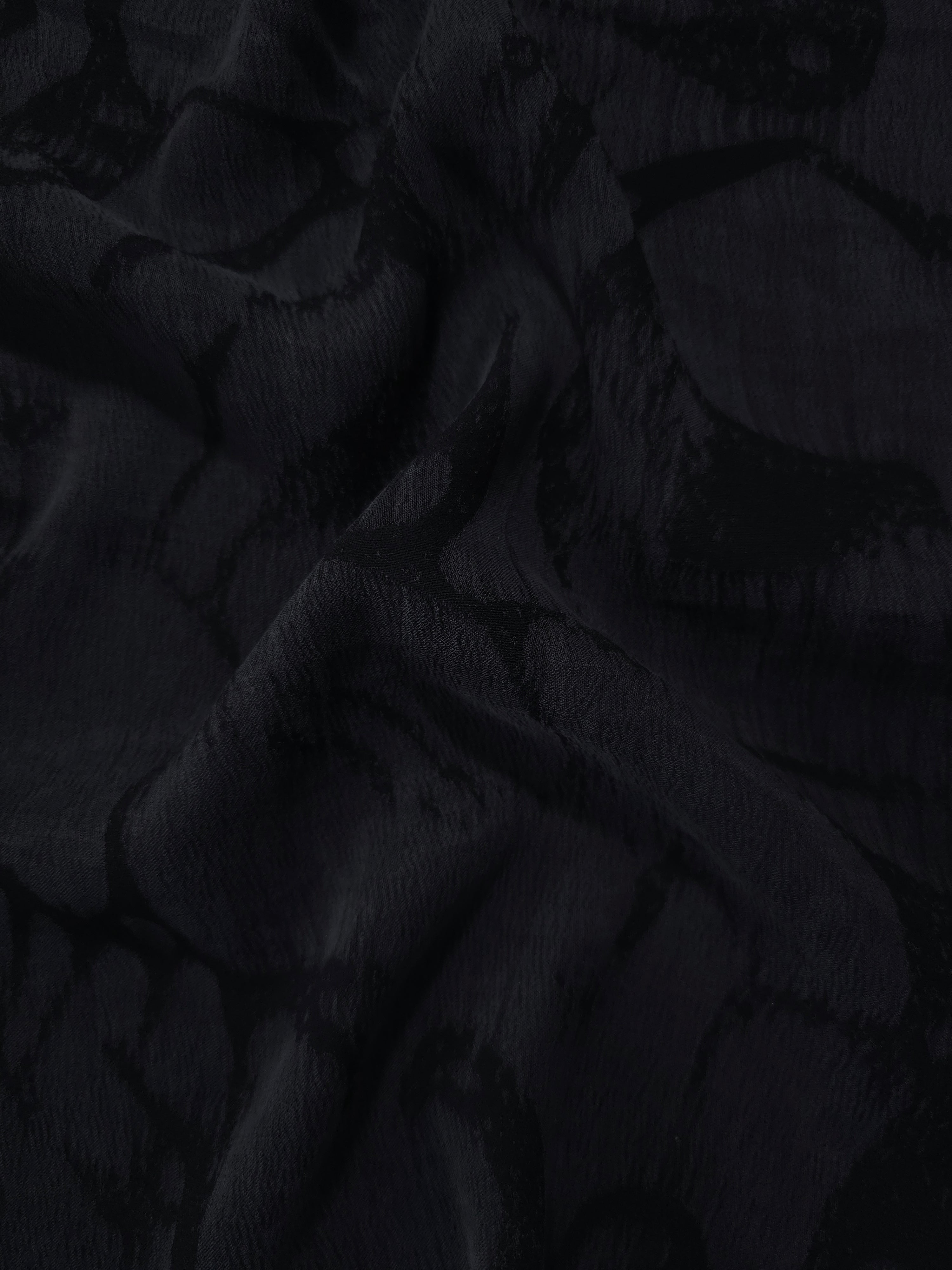 Draped black abstract scroll jacquard showing fluid texture for dresses and blouses.