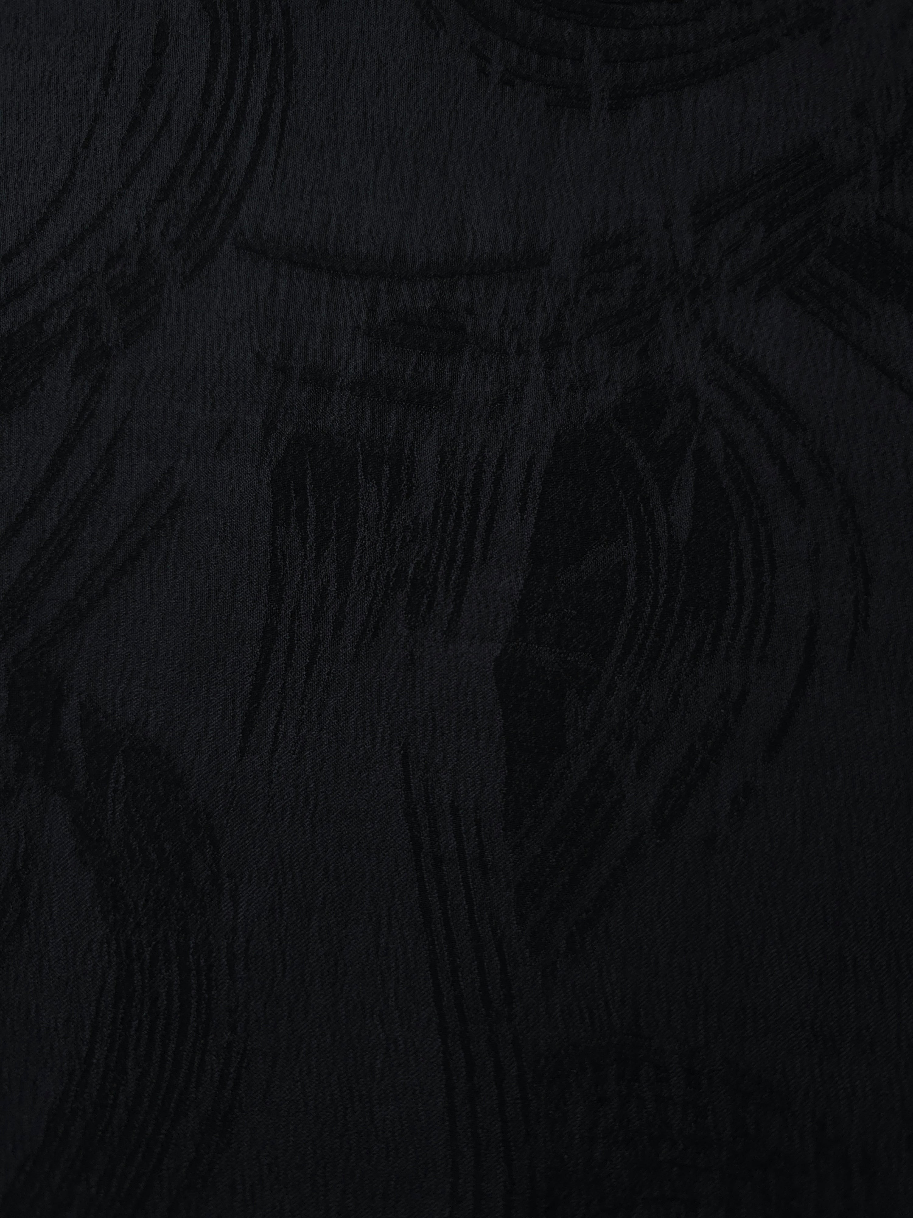 Close texture of black arc brushstroke jacquard showing smooth base and raised pattern.