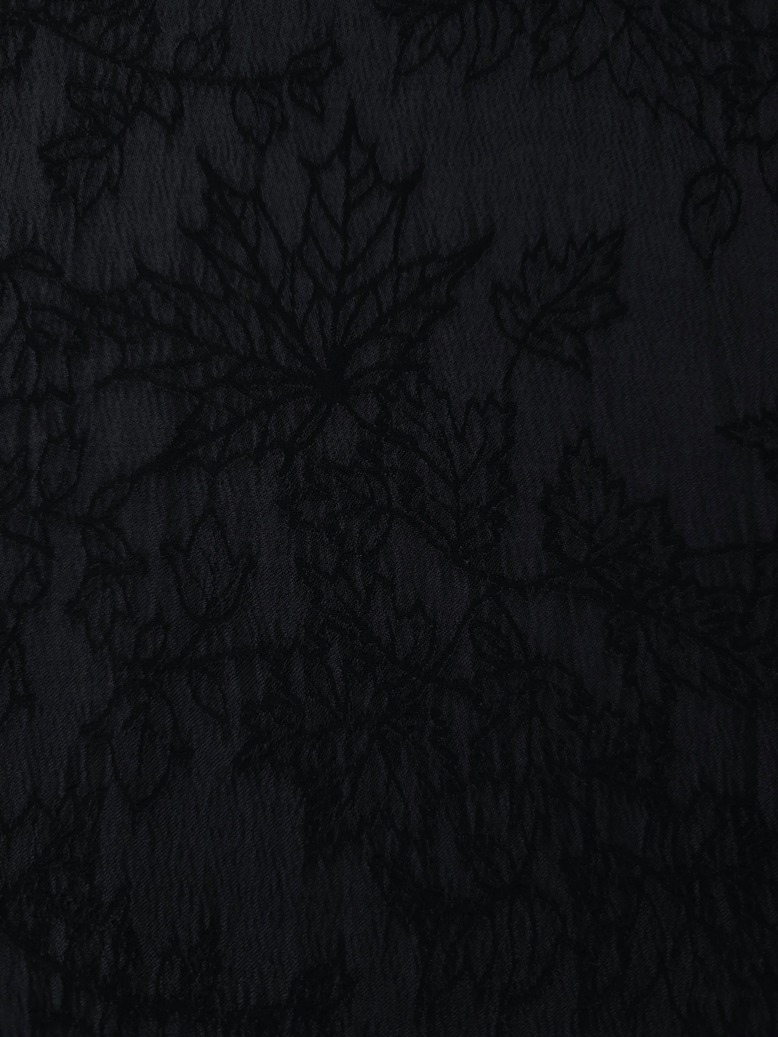 Close texture of black botanical floral jacquard showing raised floral detail.