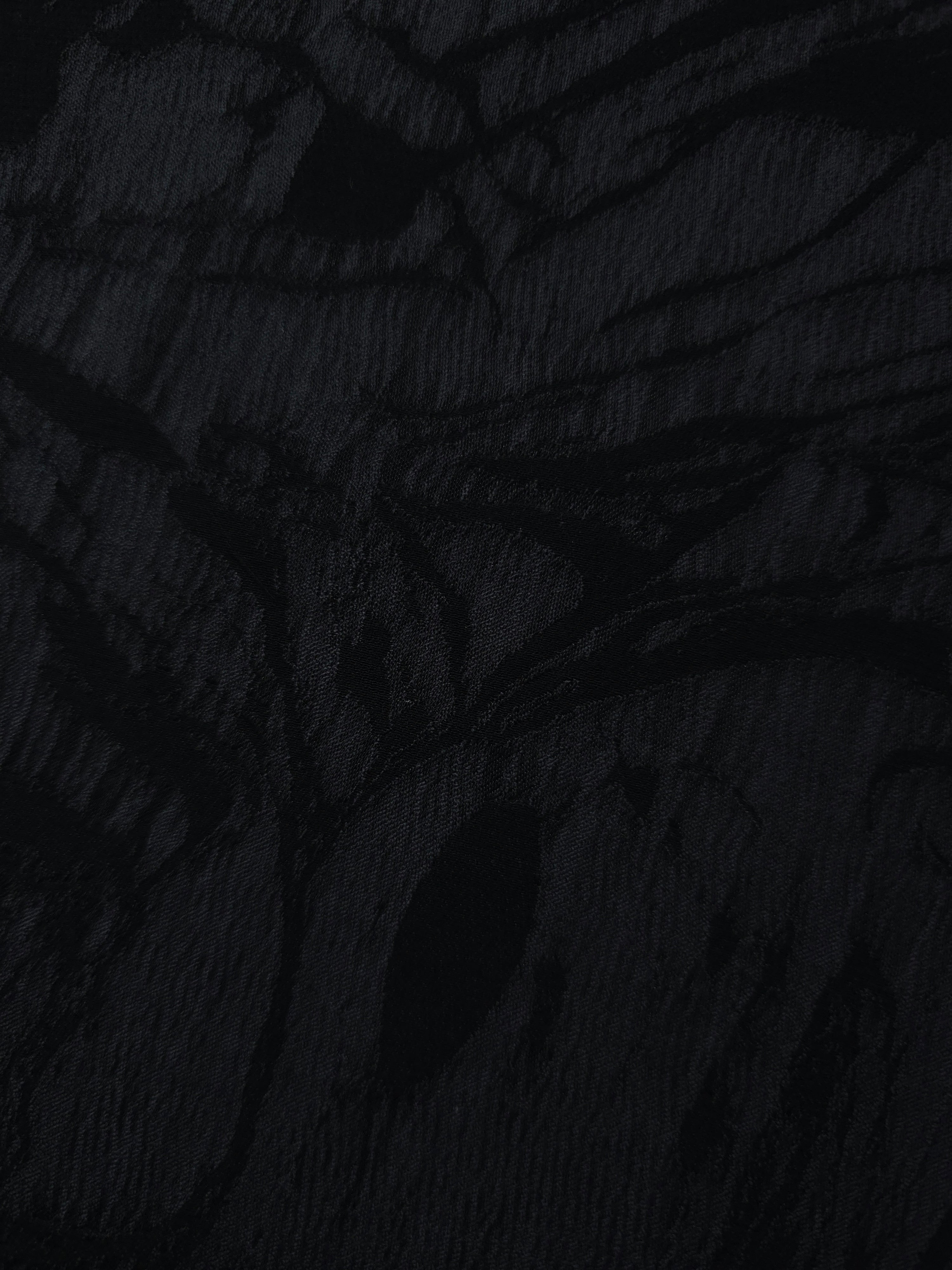 Close texture of black botanical scroll jacquard showing raised woven detail.