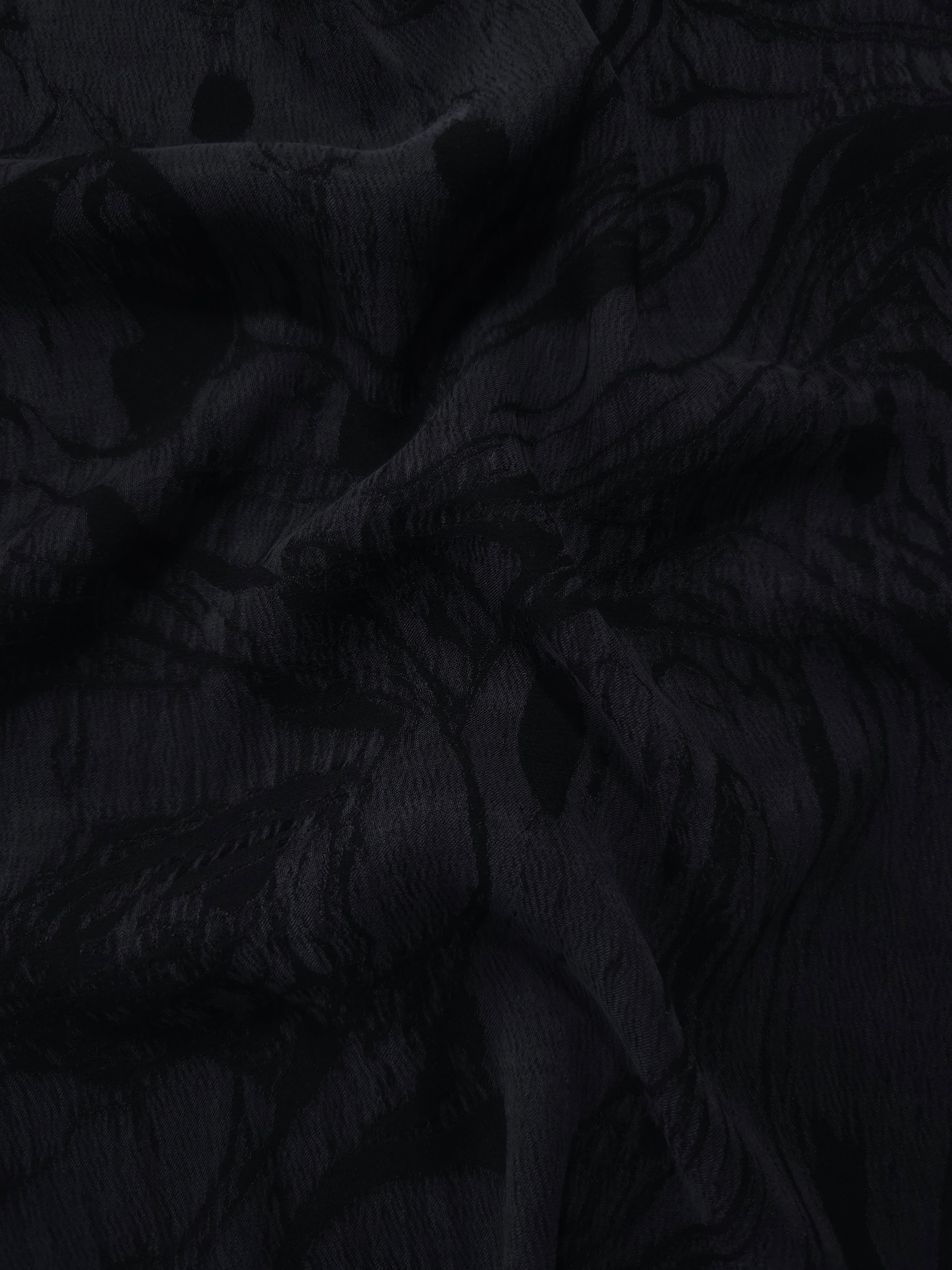 Draped black botanical scroll jacquard showing smooth flow for skirts and blouses.