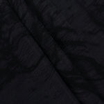 Folded black botanical scroll lyocell viscose jacquard for layered garment sewing.