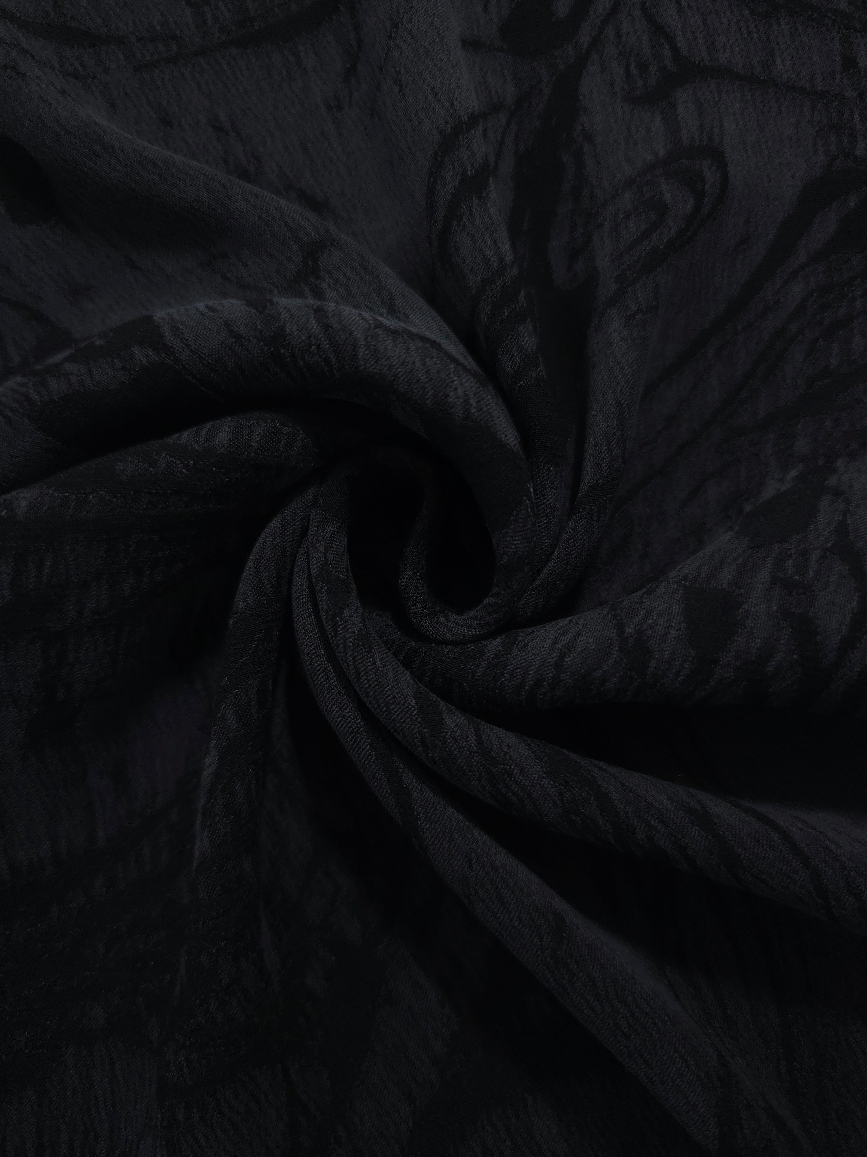 Swirl drape of black botanical scroll jacquard with darker tonal pattern.