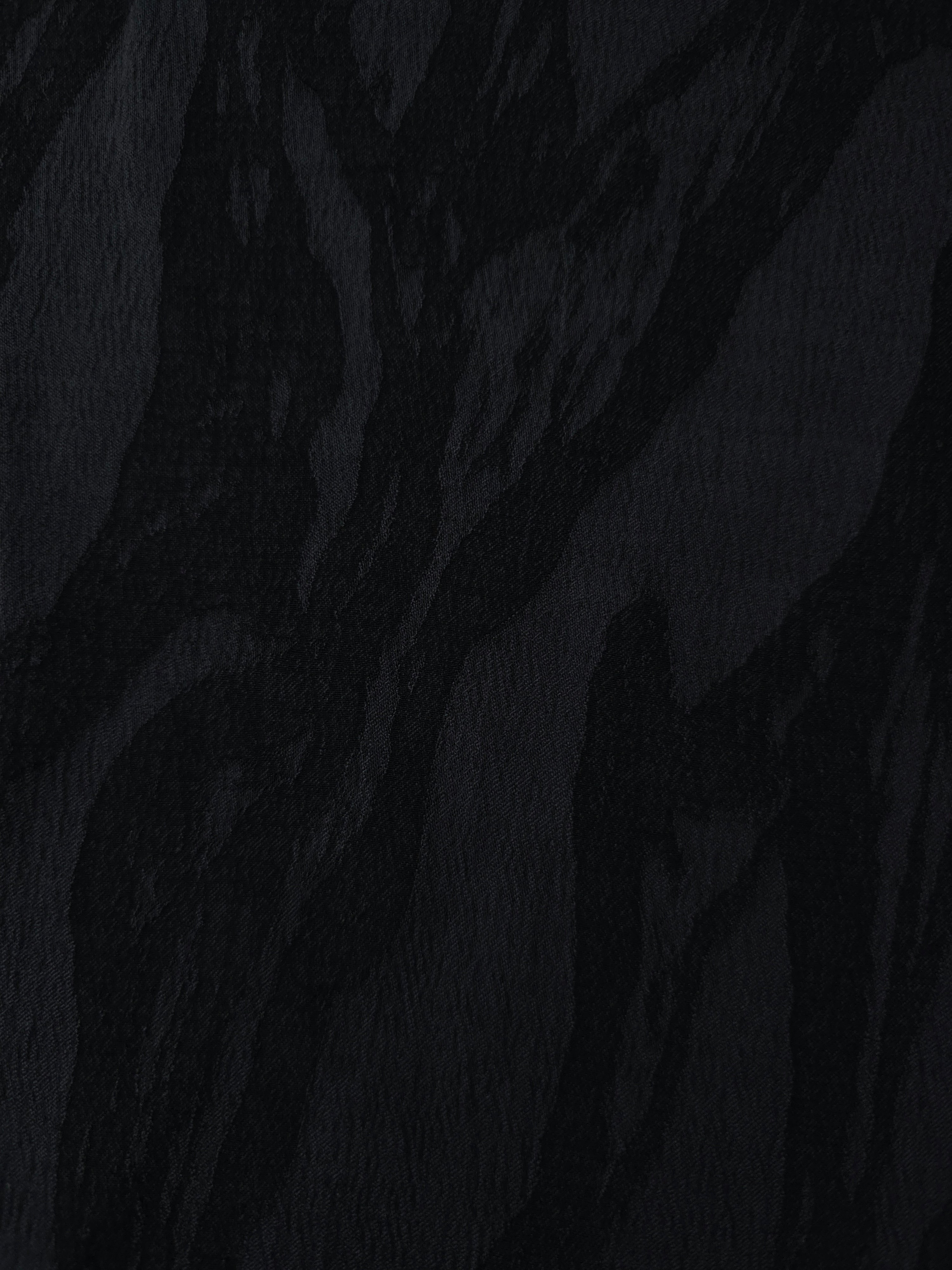 Close texture of black brushstroke leaf jacquard showing raised lyocell viscose weave.