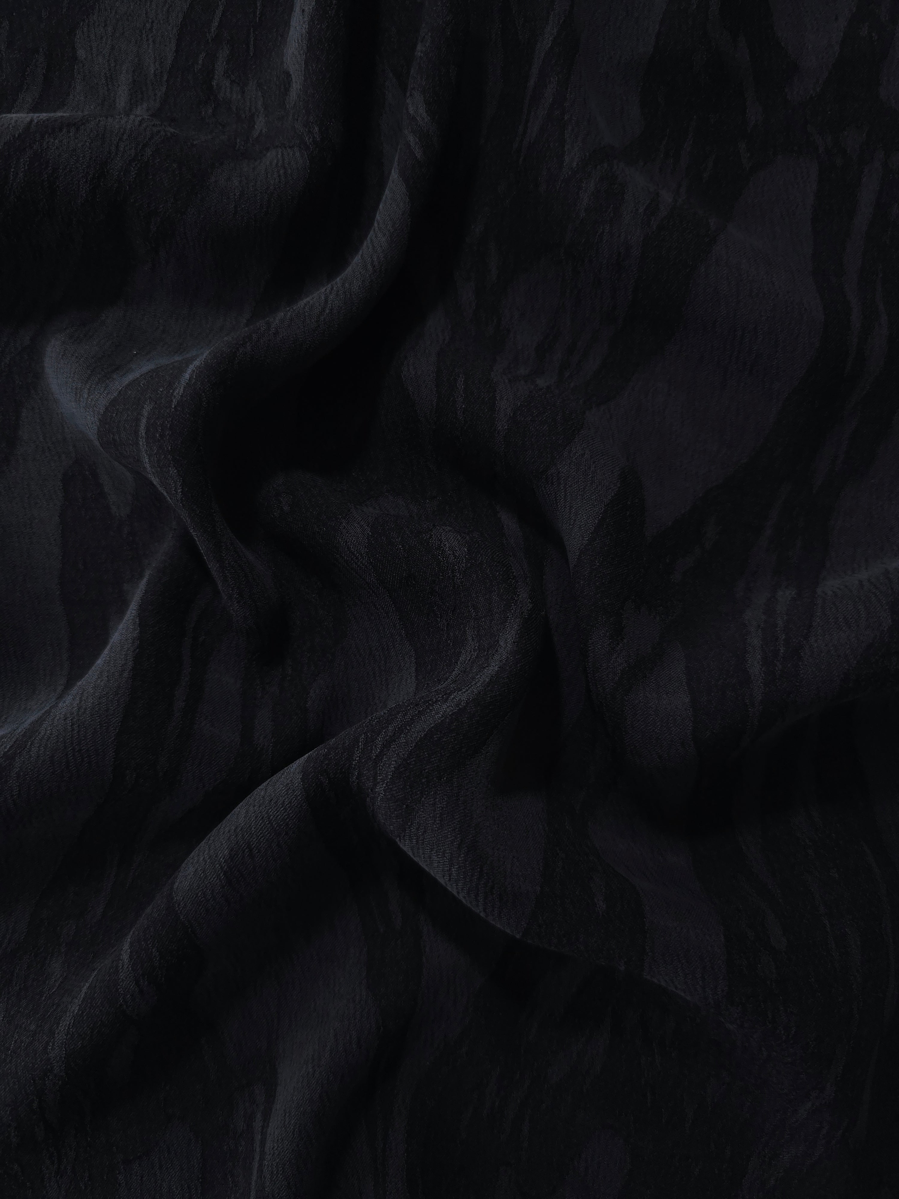Draped black brushstroke leaf jacquard showing soft structure for jackets and skirts.
