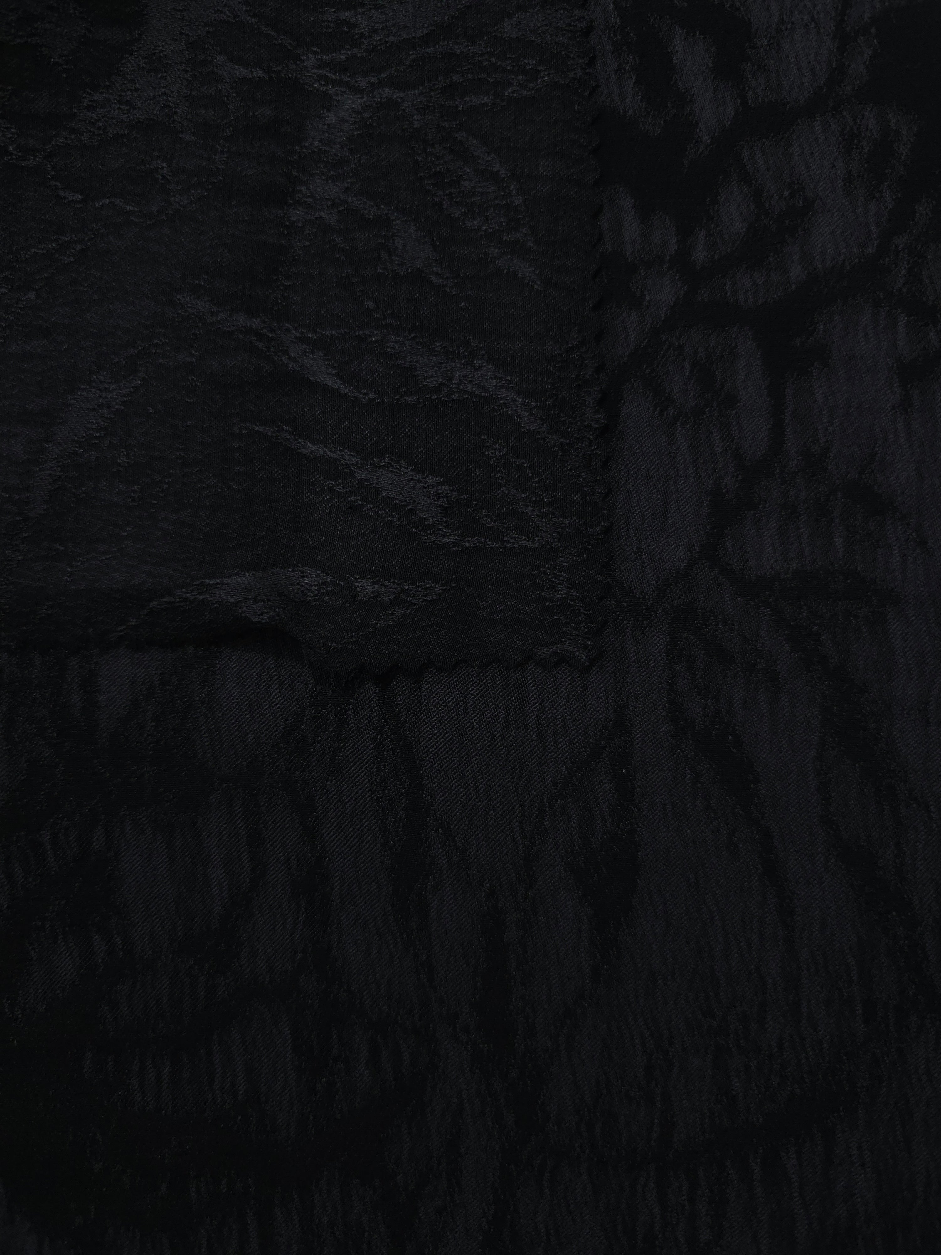 Selvage detail of black dense floral vine lyocell viscose jacquard fabric.