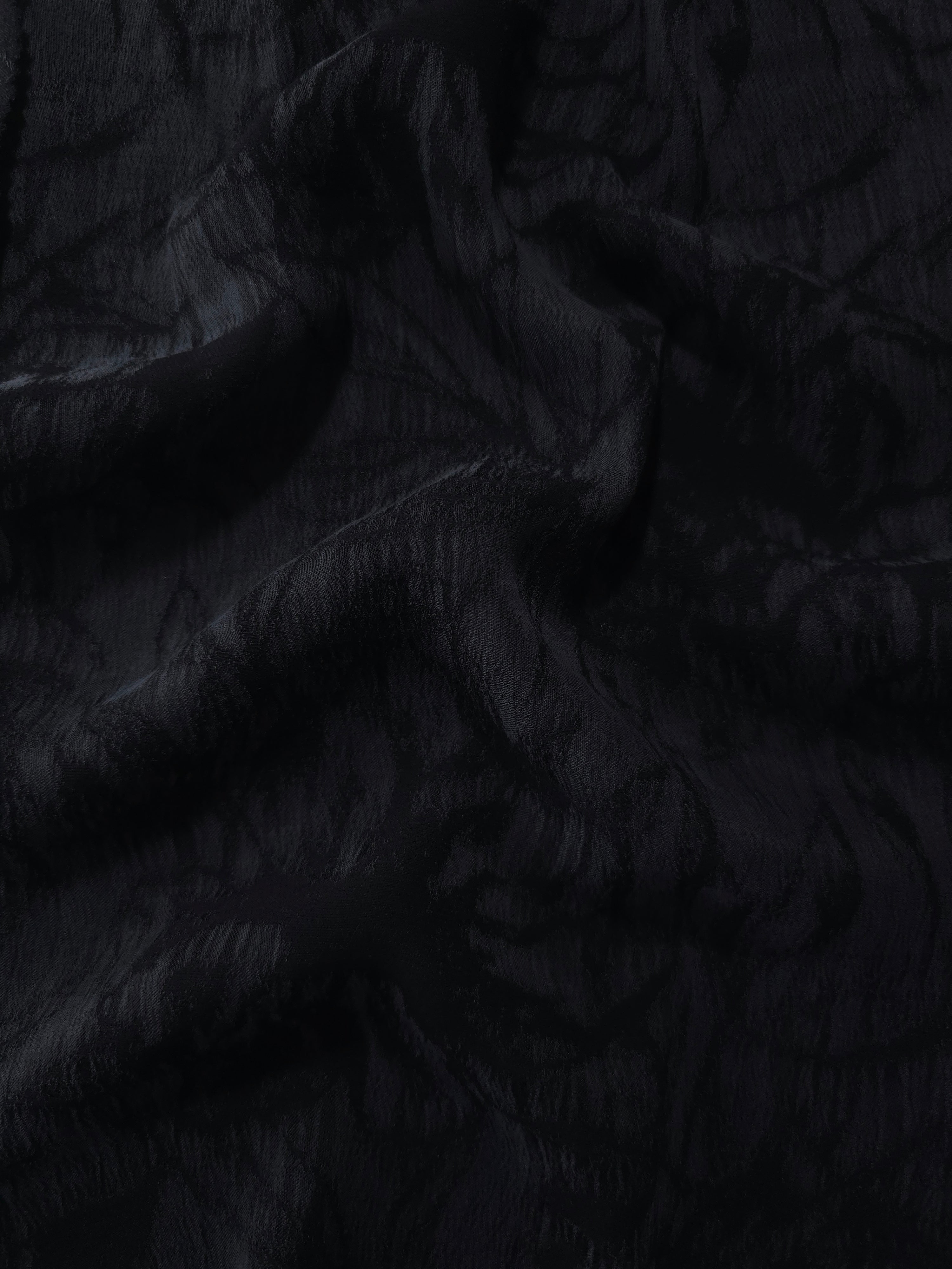 Draped black floral vine jacquard showing elegant texture for blouses and skirts.