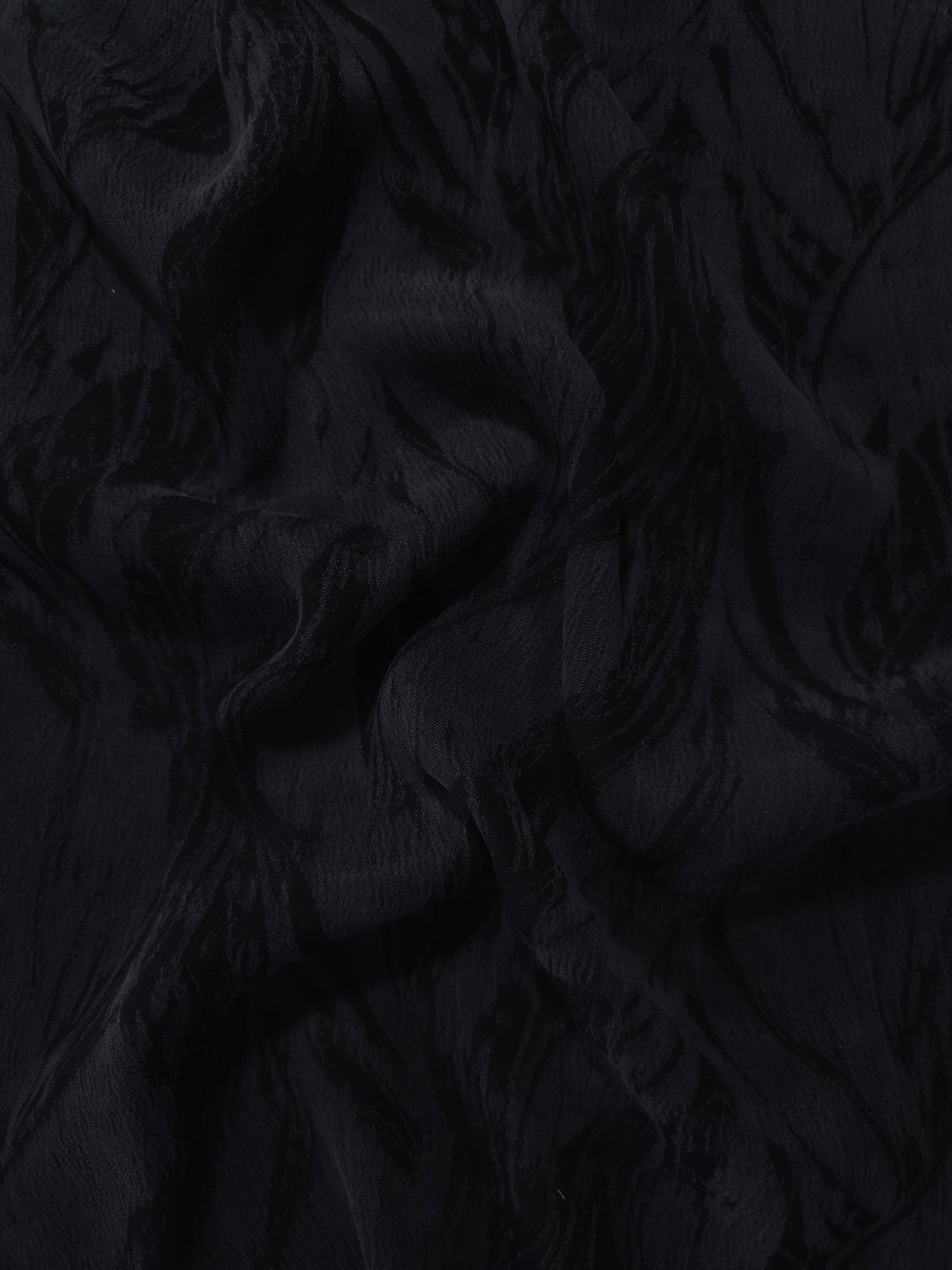 Draped black large leaf jacquard showing movement for jackets, dresses and skirts.