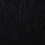 Close texture of black ornamental floral jacquard showing raised woven detail.