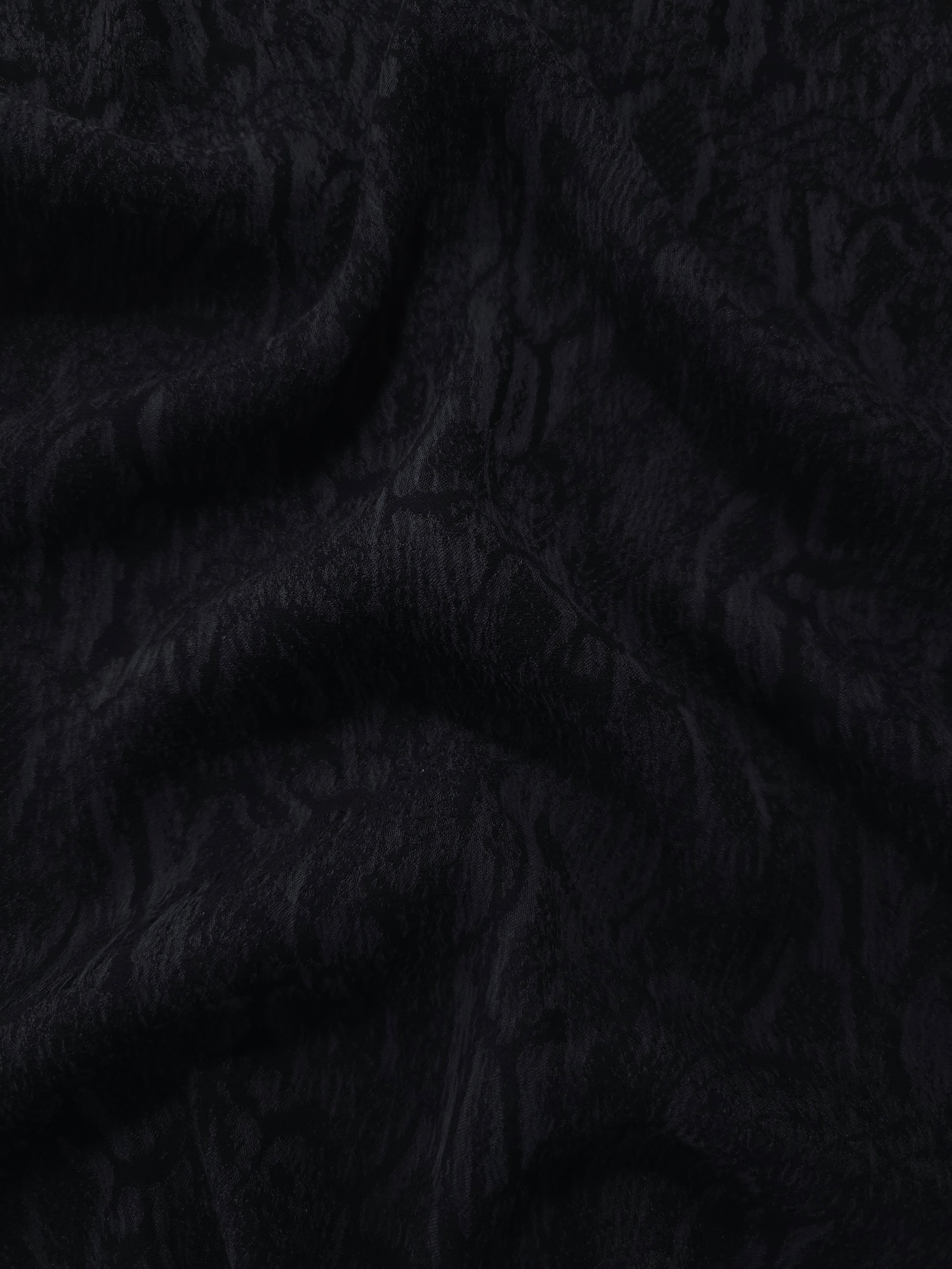 Draped black ornamental floral jacquard showing textured movement for dresses.