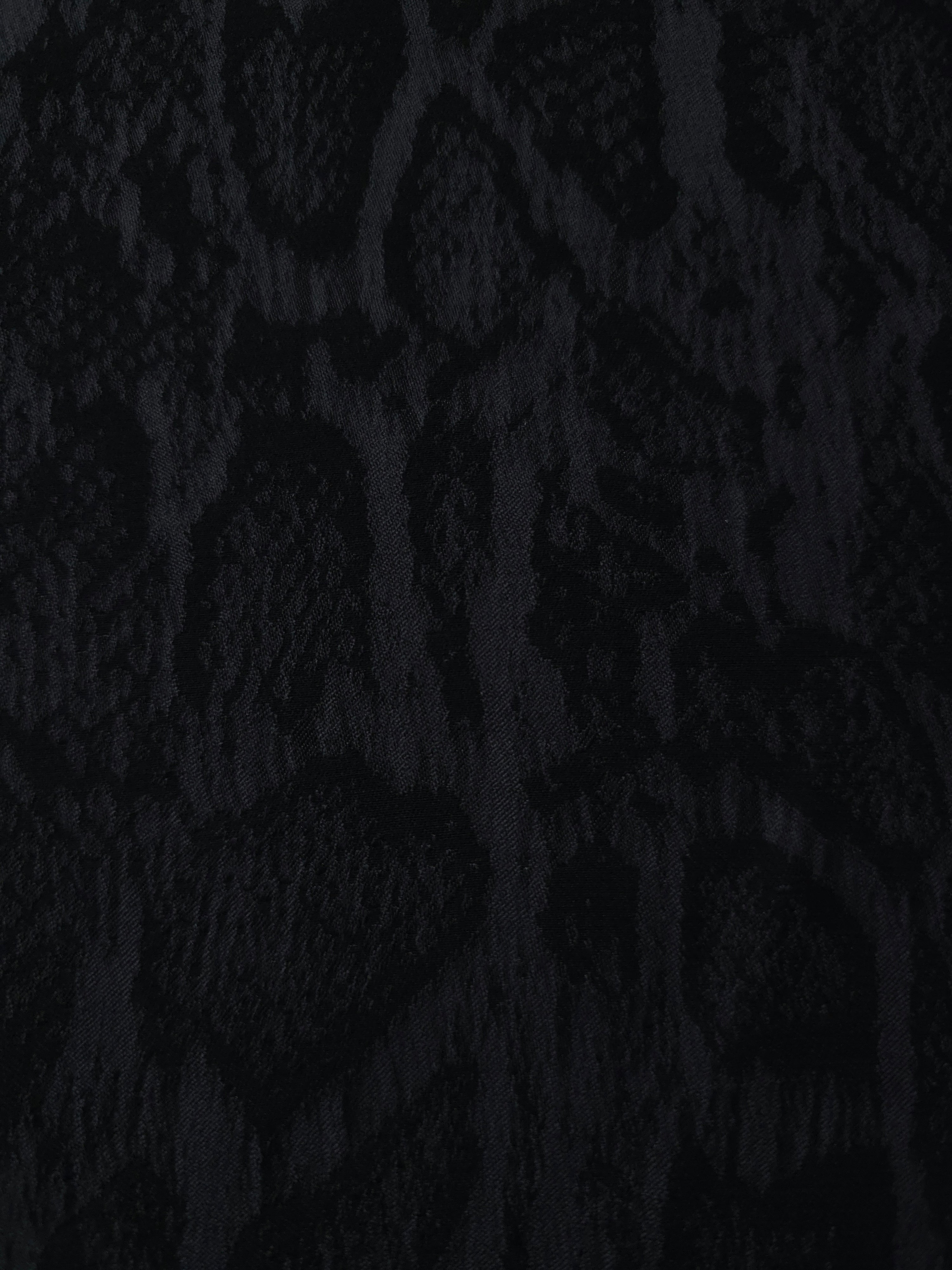 Close texture of black paisley vine jacquard showing darker raised surface detail.