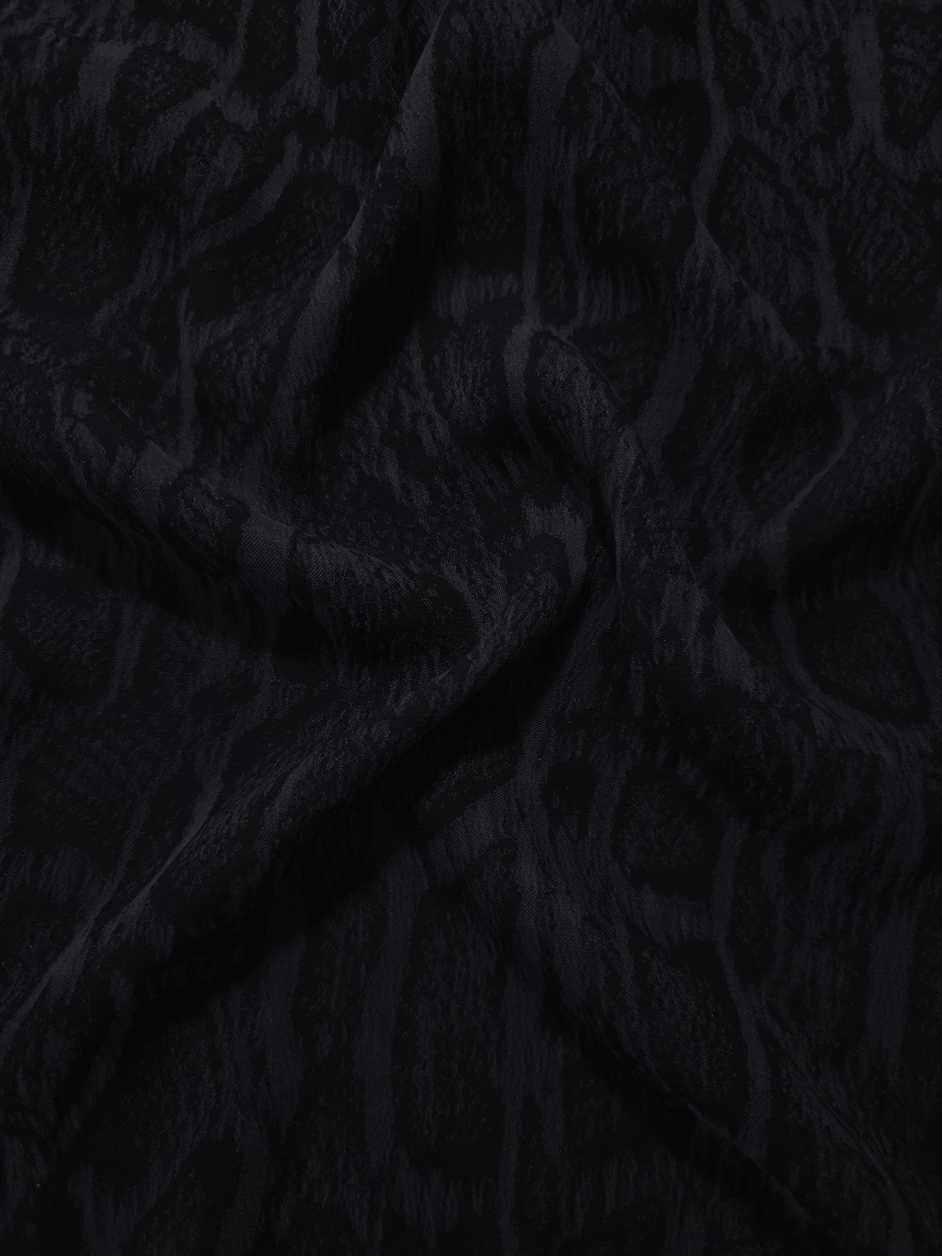 Draped black paisley vine jacquard showing fluid texture for blouses and skirts.