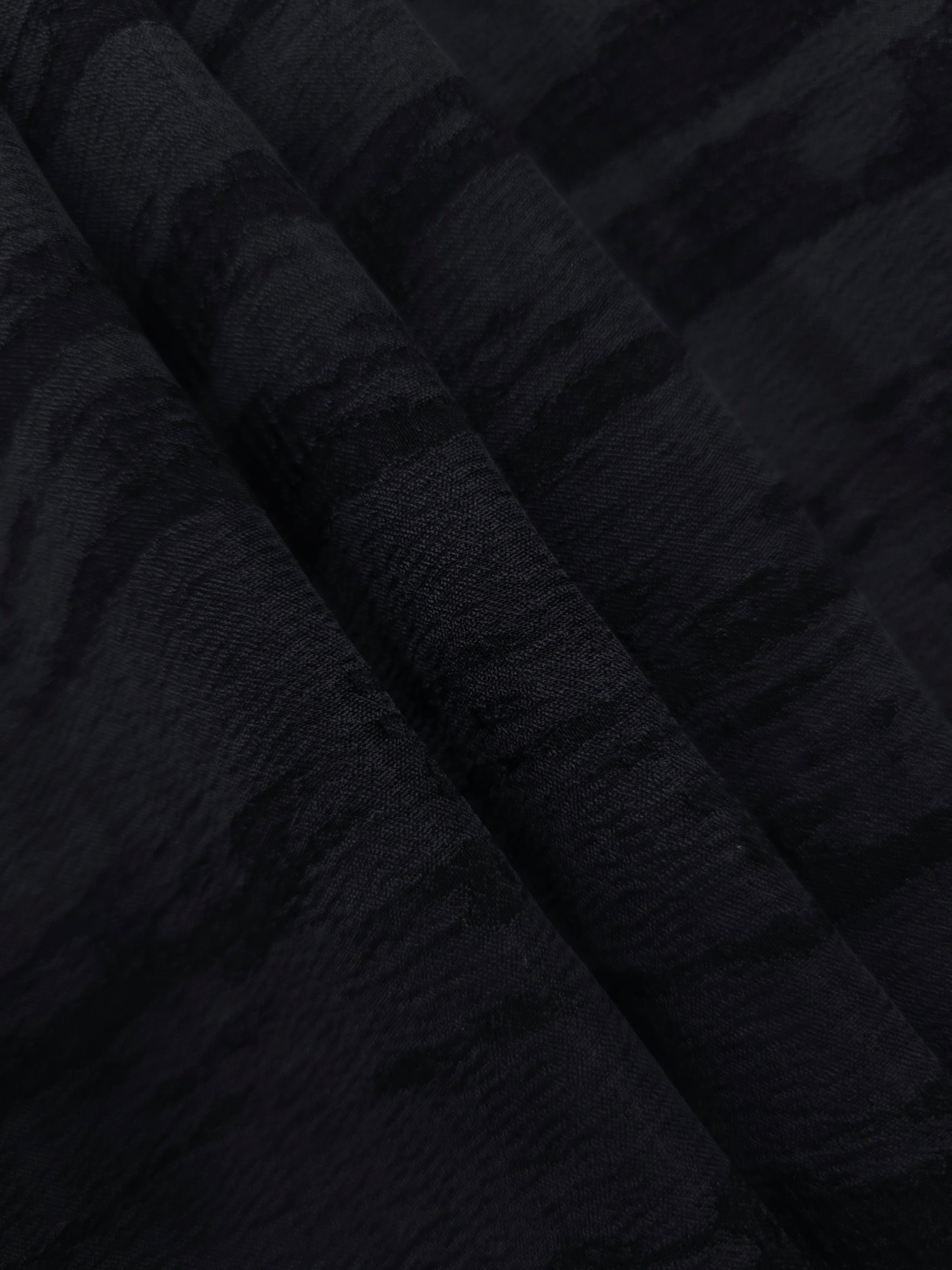 Folded tonal black vertical bark jacquard for skirts, jackets and layered garments.