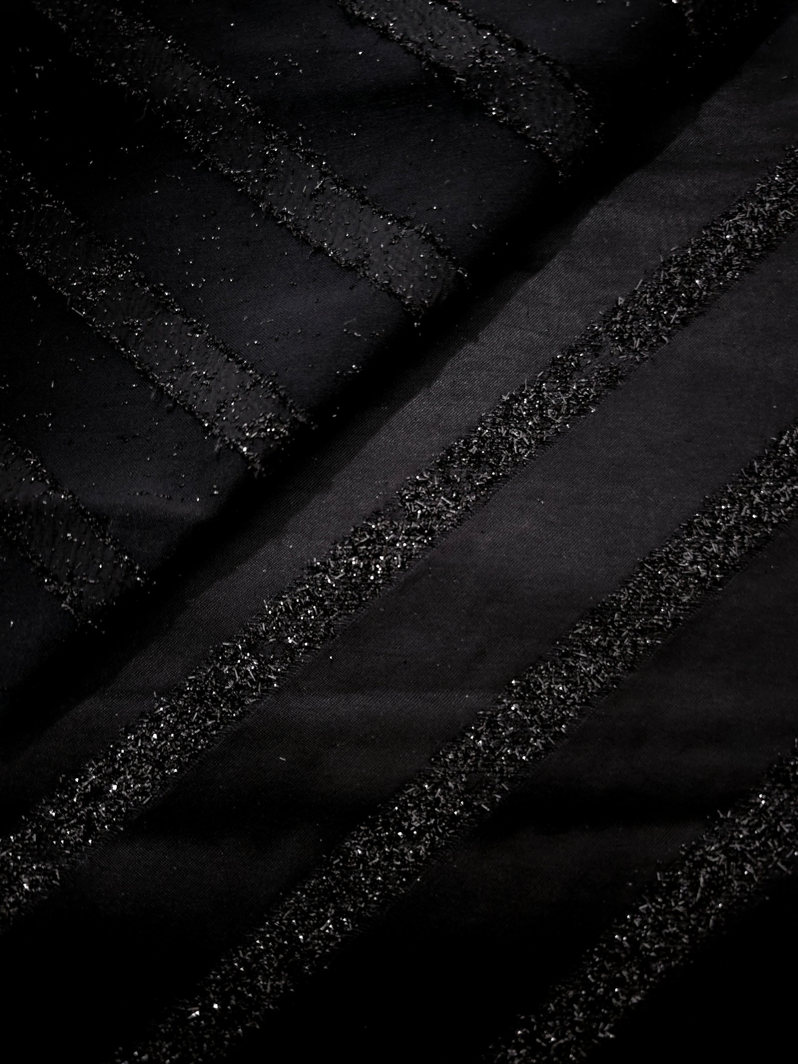Close-up of Metallic Black viscose jacquard with embossed linear pinstripes
