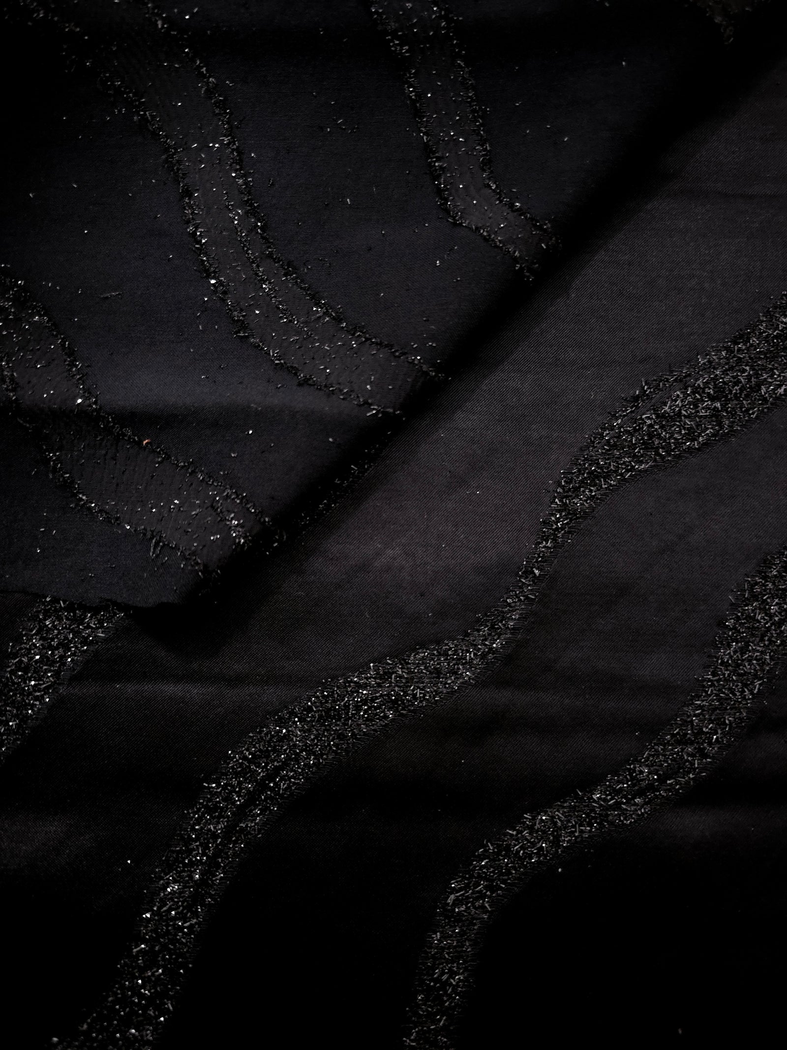 Close-up of Metallic Black viscose jacquard with embossed ripple stripe pattern