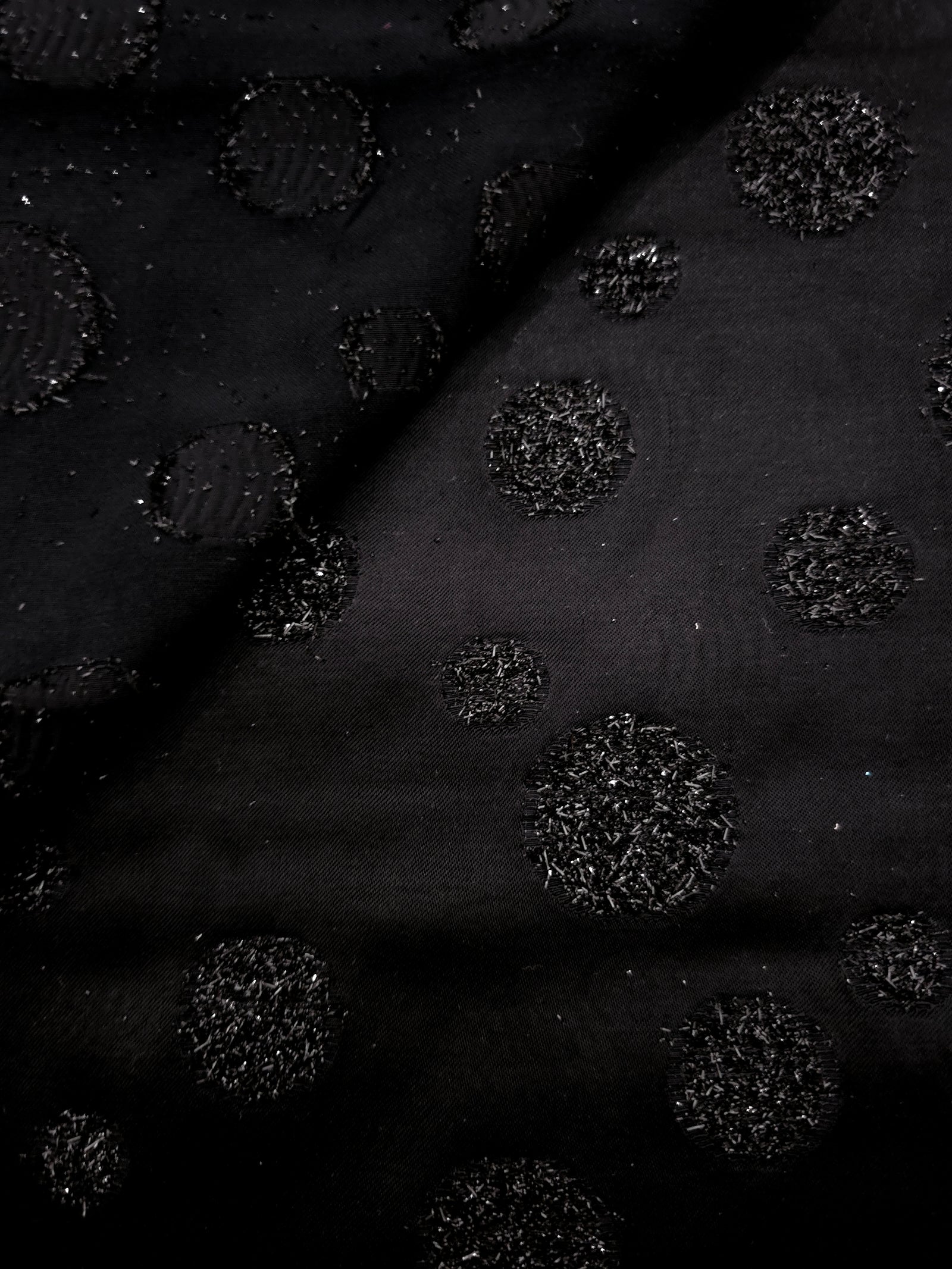 Close-up of Metallic Black viscose jacquard with embossed speckled confetti dots
