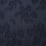 Close texture of blue lyocell viscose jacquard with raised floral pattern for sewing projects.