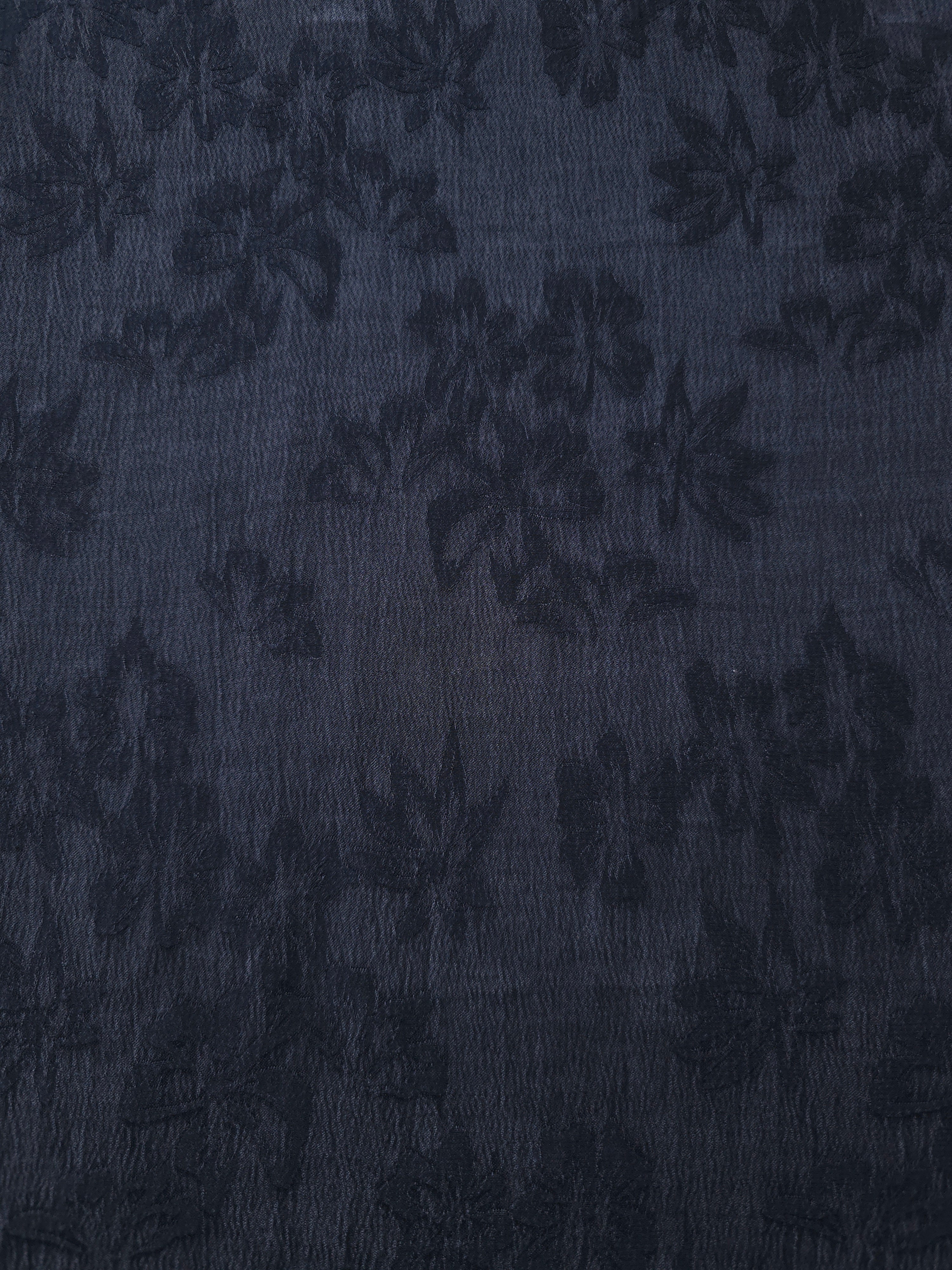 Close texture of blue lyocell viscose jacquard with raised floral pattern for sewing projects.