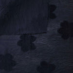 Pattern detail of dark blue flower embossed viscose jacquard fabric with raised motif.