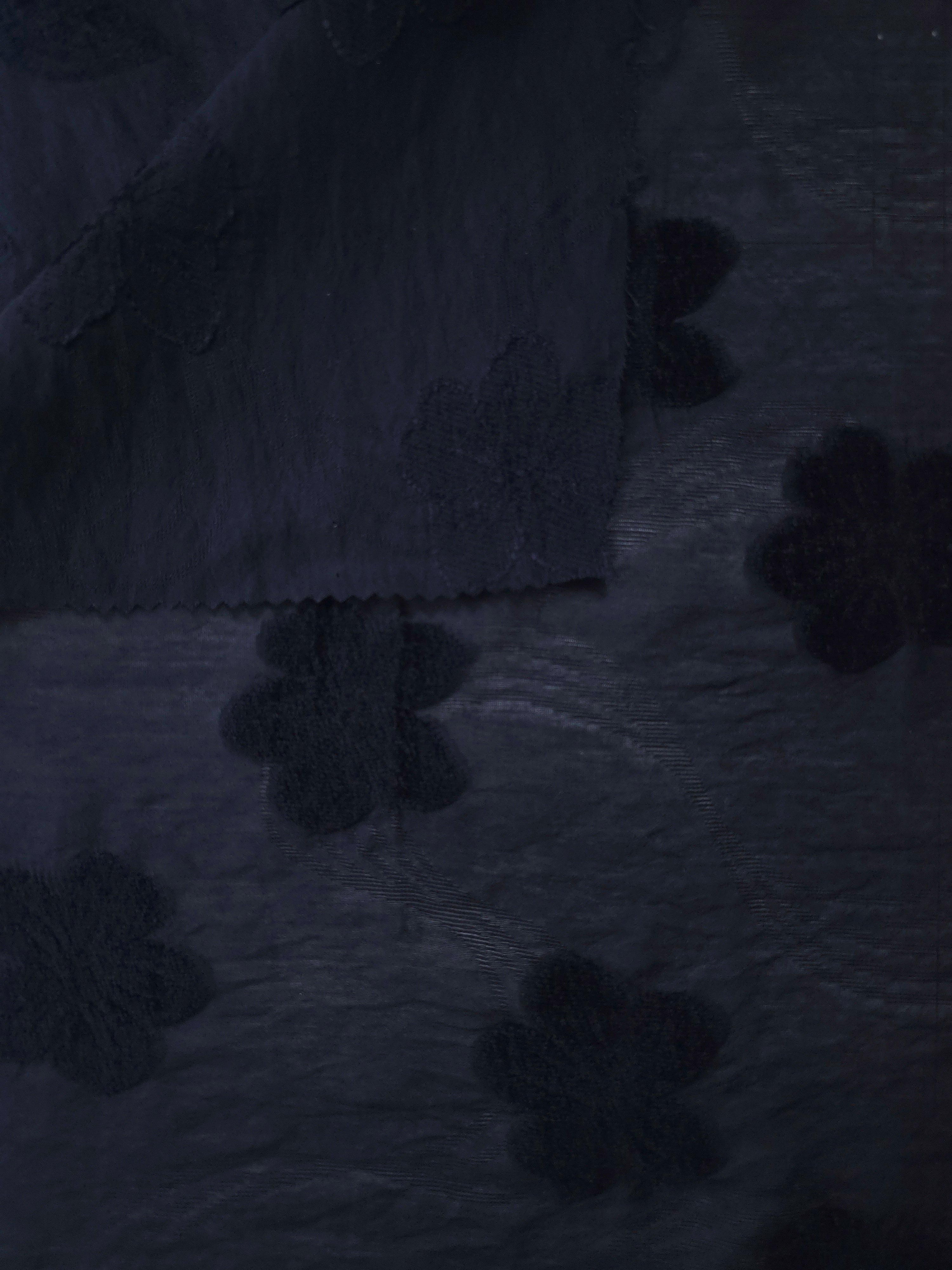 Pattern detail of dark blue flower embossed viscose jacquard fabric with raised motif.
