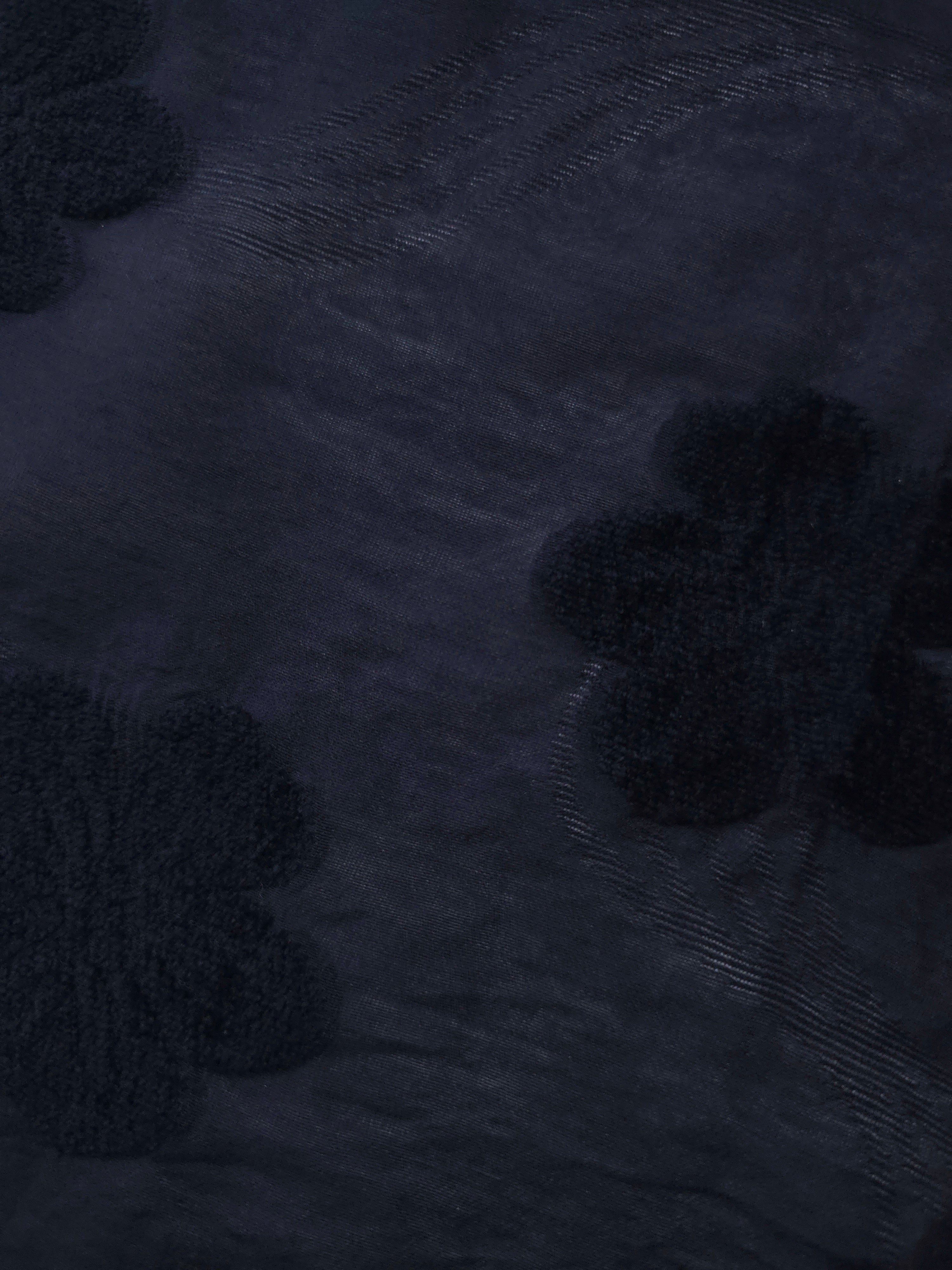 Wave drape of dark blue flower embossed viscose jacquard fabric for layered dresses.