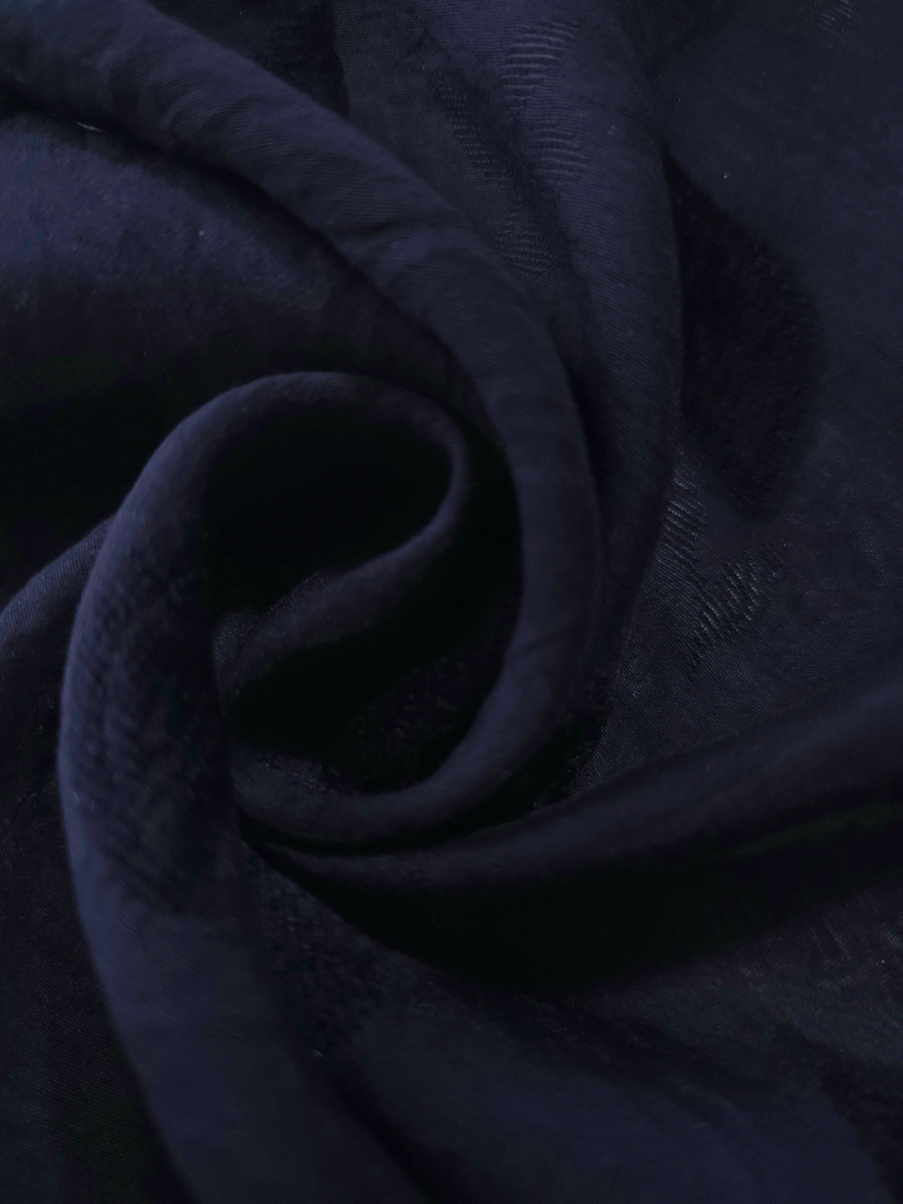 Dark blue leaf embossed viscose jacquard fabric in a close draped view for overlays.