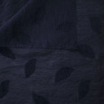 Pattern detail of dark blue leaf embossed viscose jacquard fabric with raised motif.