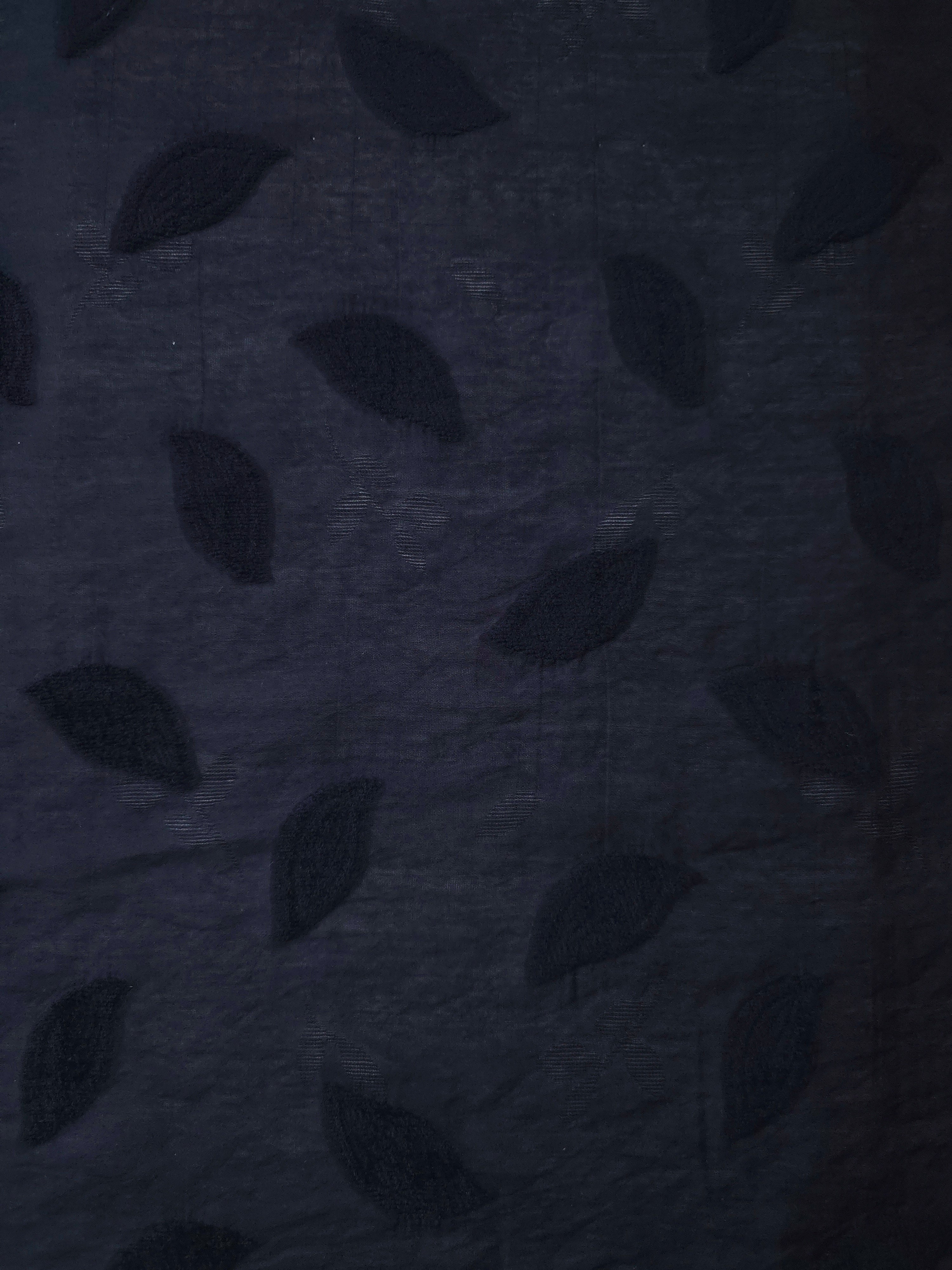 Wide view of dark blue leaf embossed viscose jacquard fabric with tonal raised texture.