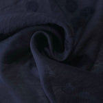 Swirl drape of dark blue small leaf embossed viscose jacquard fabric for kaftan overlays.