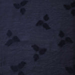 Drape view of dark blue small leaf embossed viscose jacquard fabric for sheer garment layers.